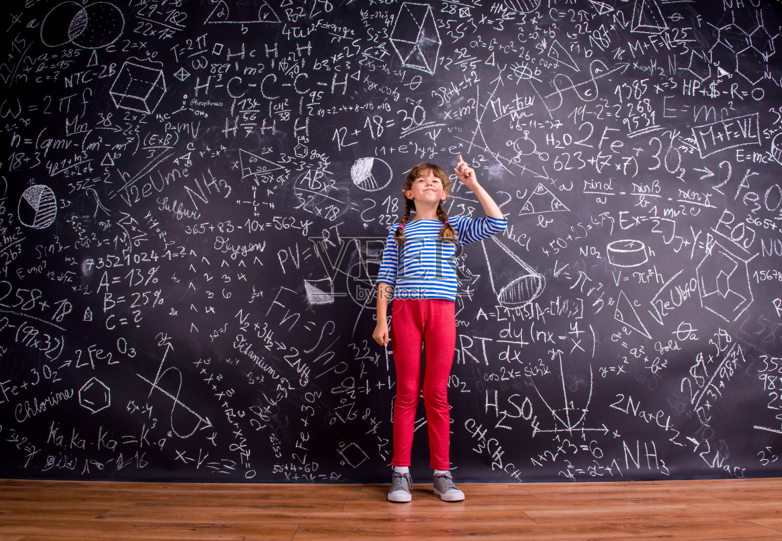 两个辫子的女孩，大黑板上写着数学符号照片摄影图片