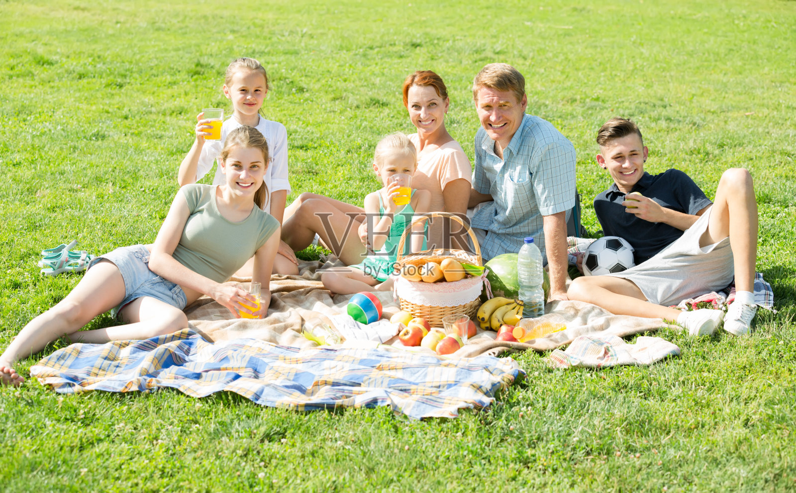 活跃的大家庭在公园的绿色草坪上野餐照片摄影图片