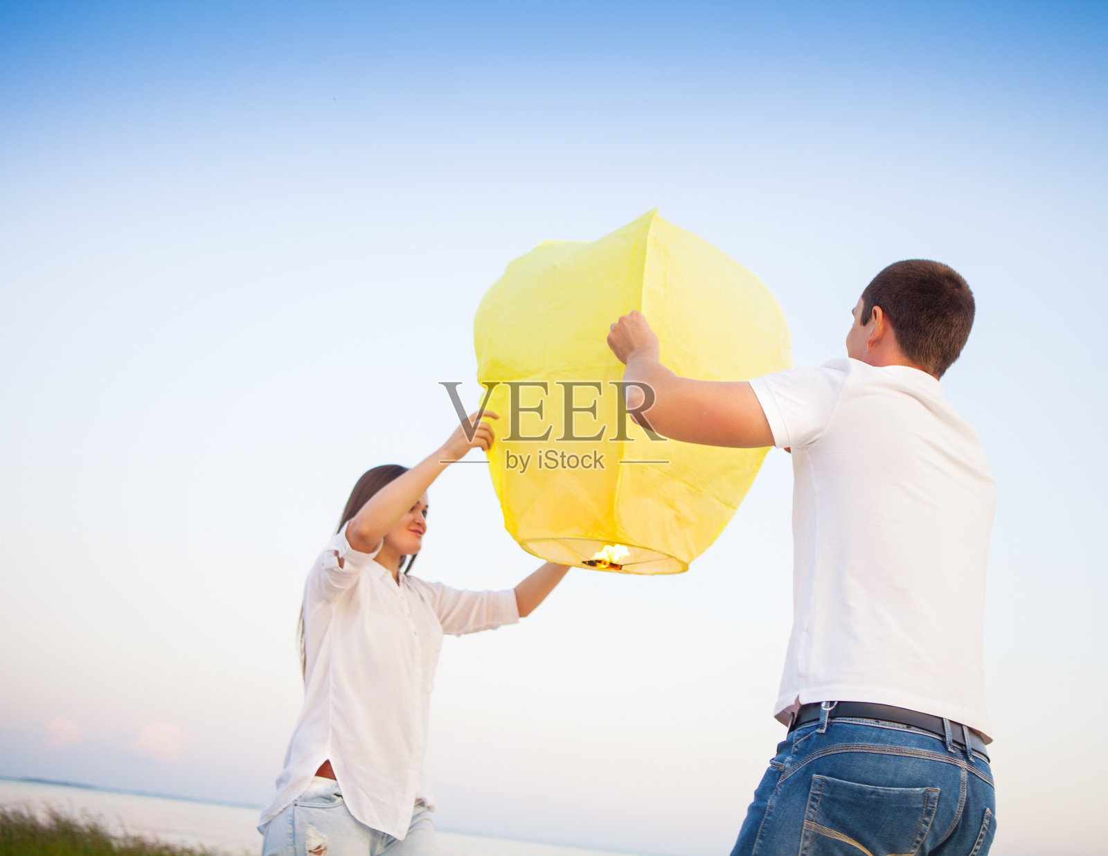 年轻夫妇开始在海边挂上黄色的中国天灯照片摄影图片