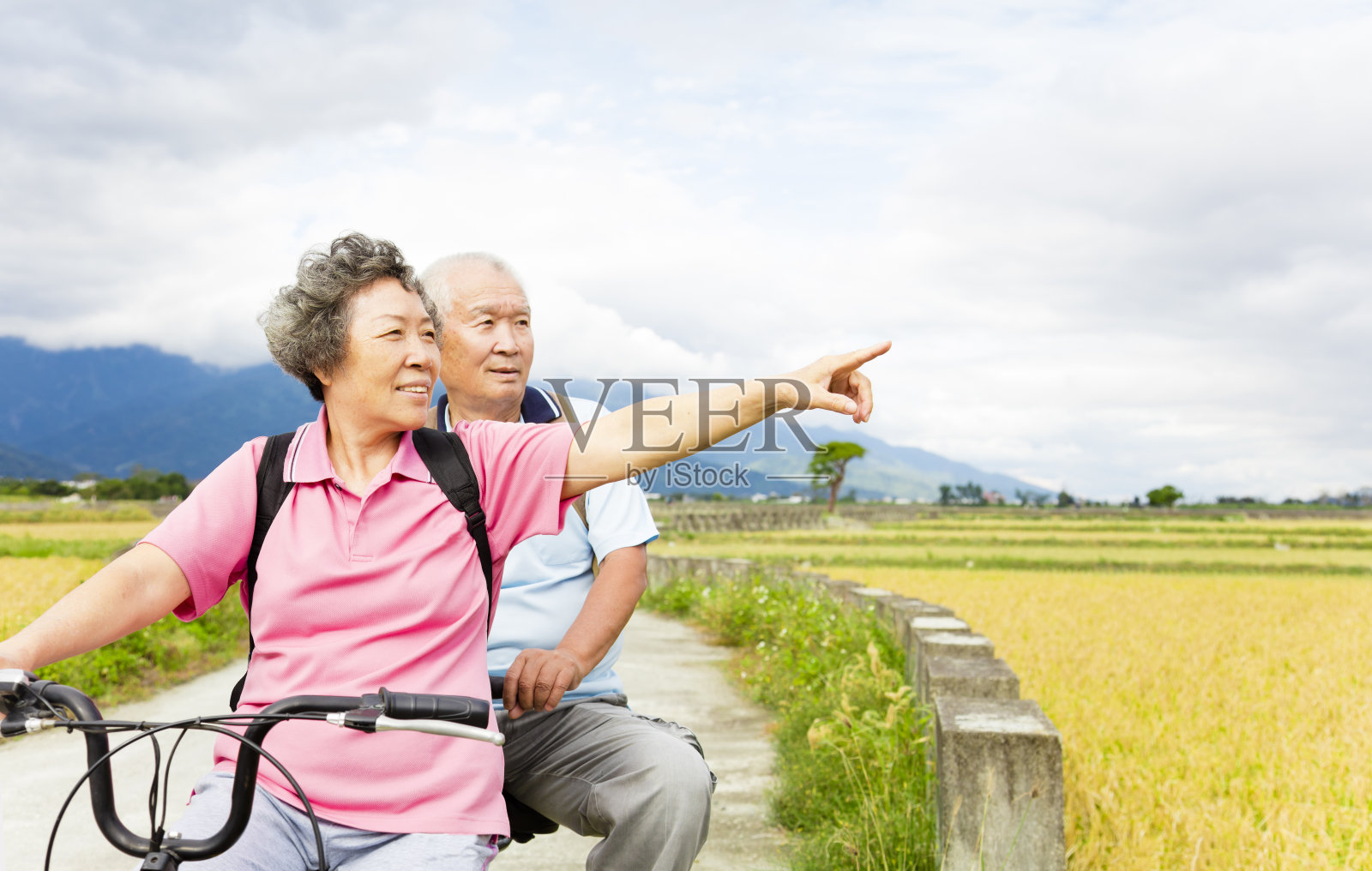 快乐的老夫妇在乡村公路上骑自行车照片摄影图片