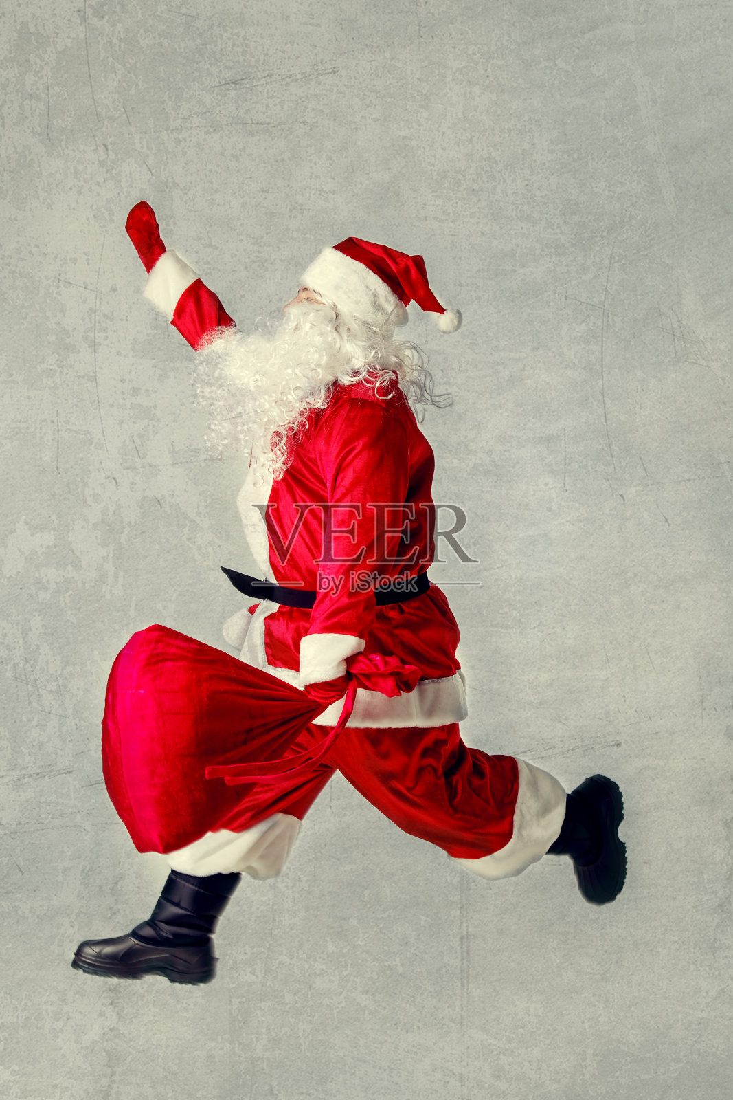 圣诞老人带着一袋礼物跑着。照片摄影图片