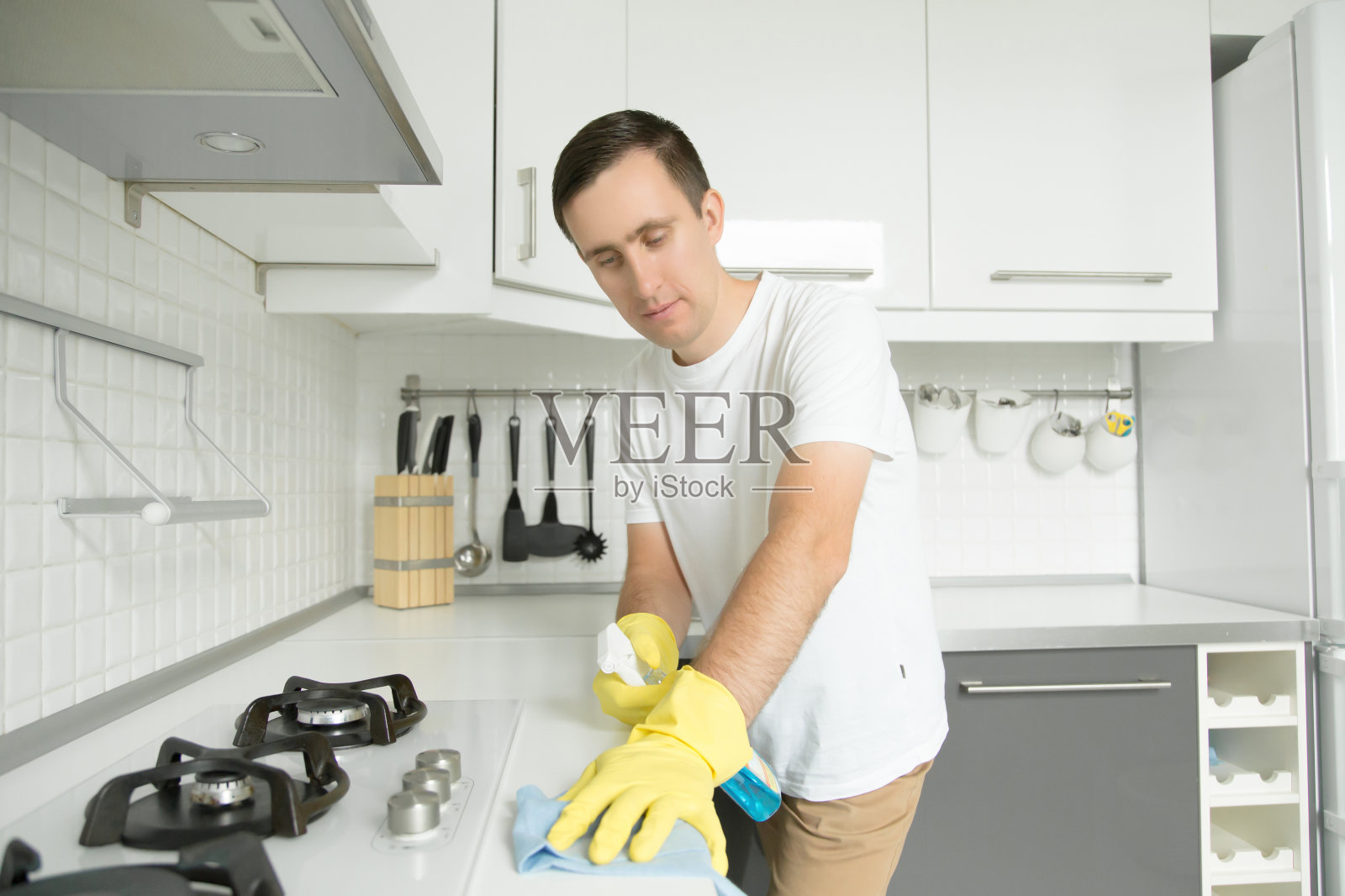 年轻严肃的男人戴着黄色橡胶手套在打扫火炉照片摄影图片