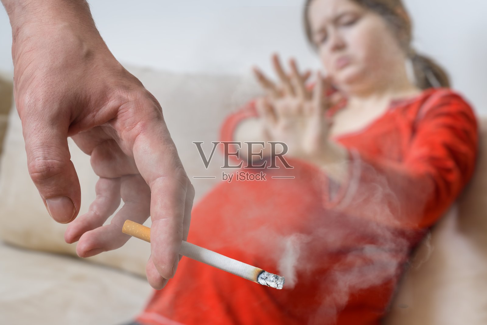 怀孕期间被动吸烟。自私的人在吸烟。背景里有个孕妇。照片摄影图片
