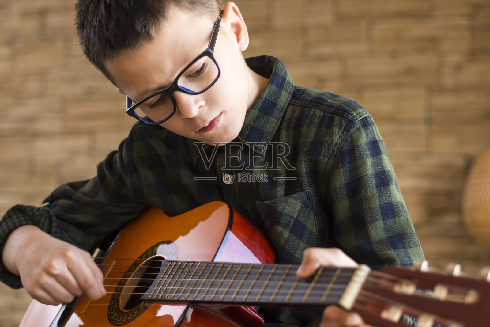 戴眼镜的男孩在客厅弹原声吉他照片摄影图片