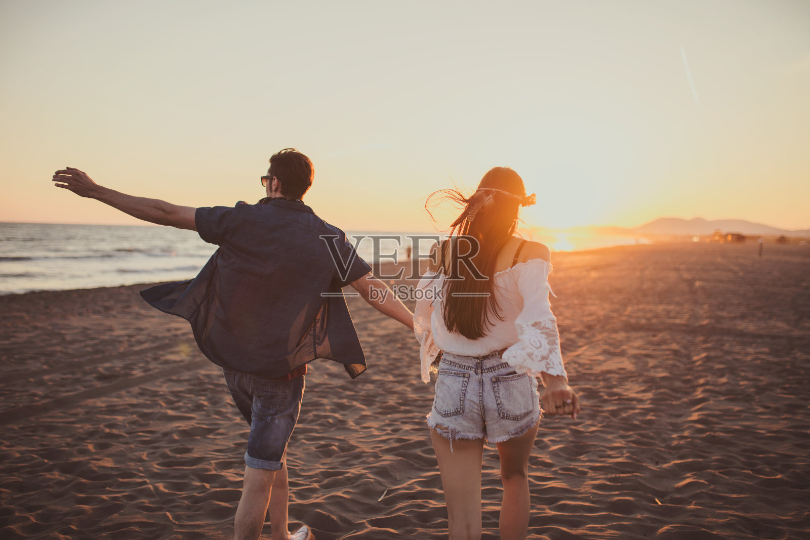 情侣们手牵着手在沙滩上自由奔跑照片摄影图片