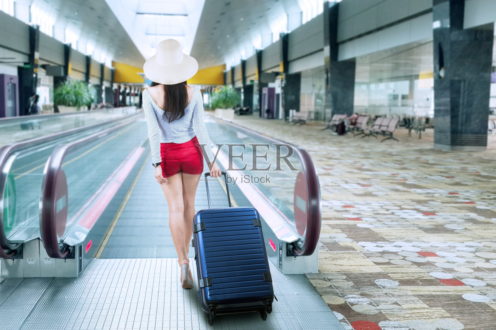 一个年轻女子带着行李箱在机场照片摄影图片