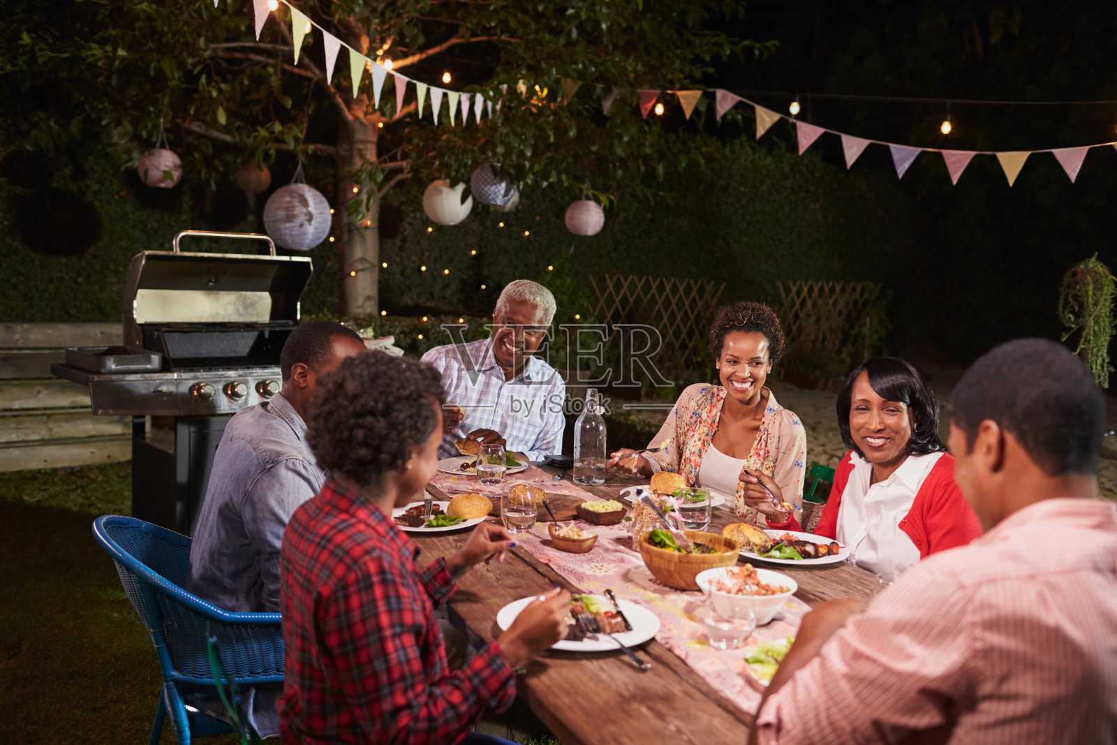 成年黑人家庭在他们的花园里一起享用晚餐照片摄影图片