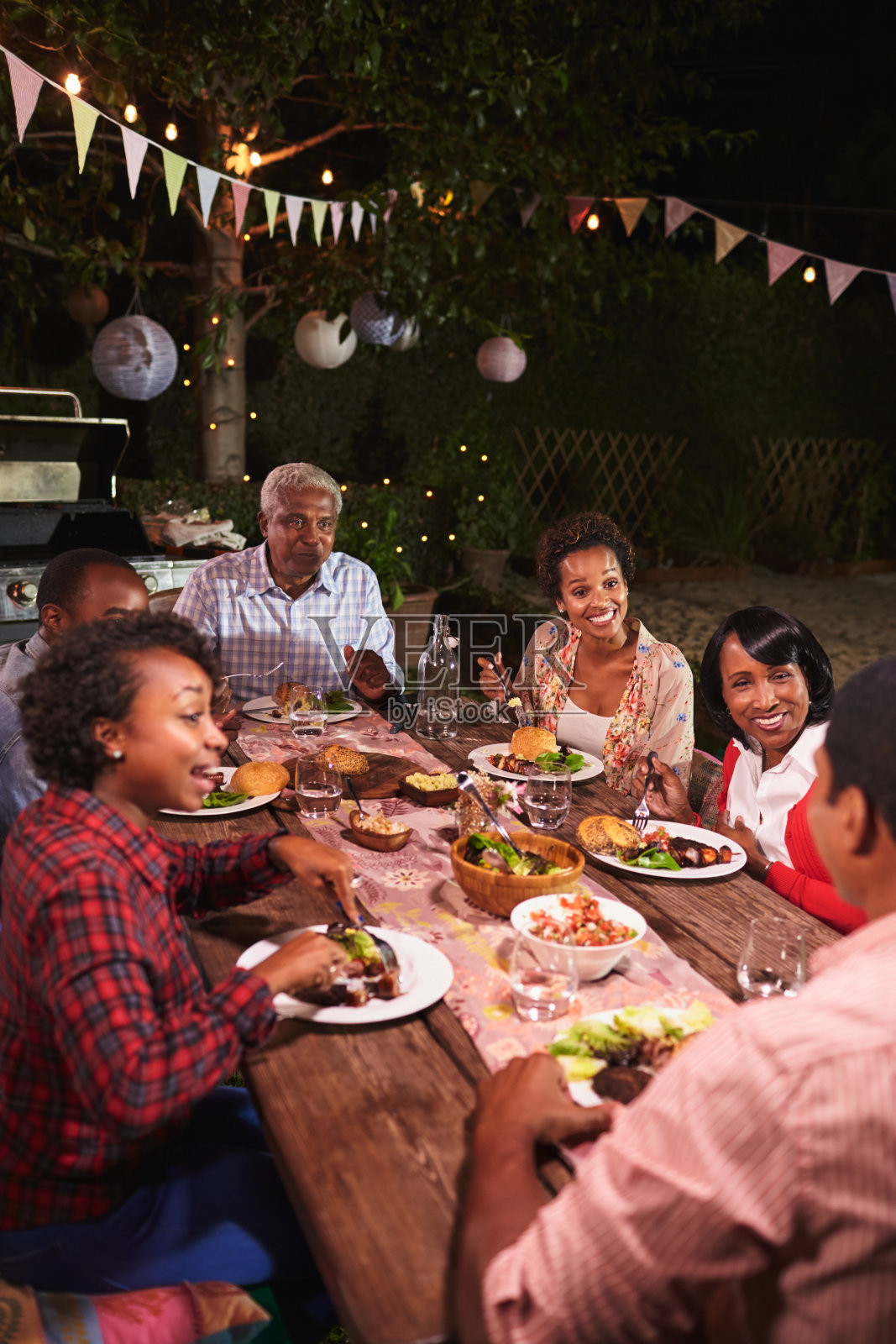 成年黑人家庭在花园一起享受晚餐，垂直照片摄影图片