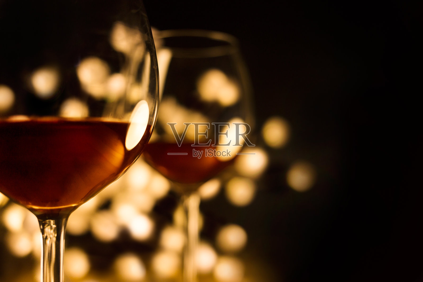 两杯红酒配上美丽的灯光，黑色的背景照片摄影图片