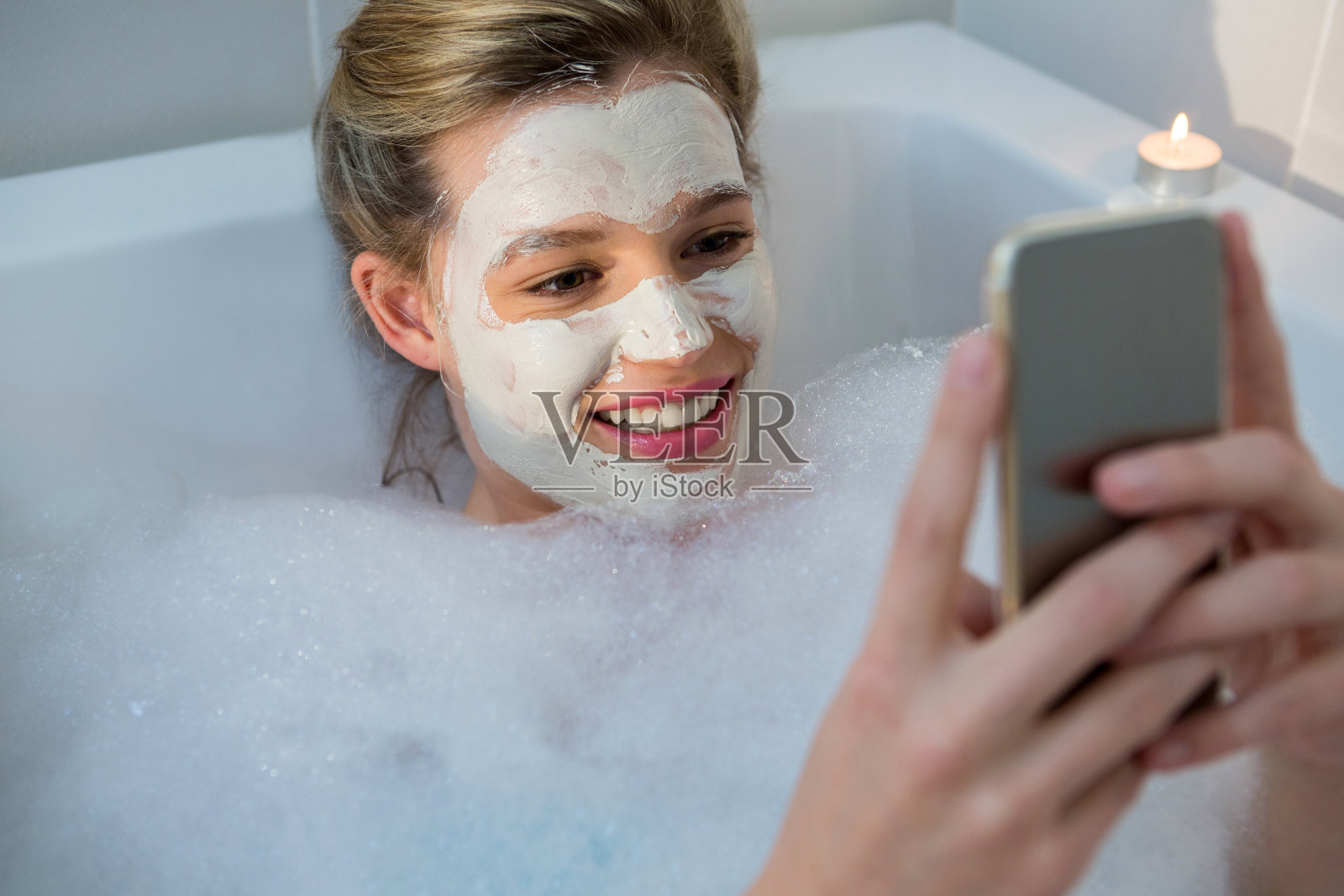 在浴缸里洗澡时使用手机的女人照片摄影图片