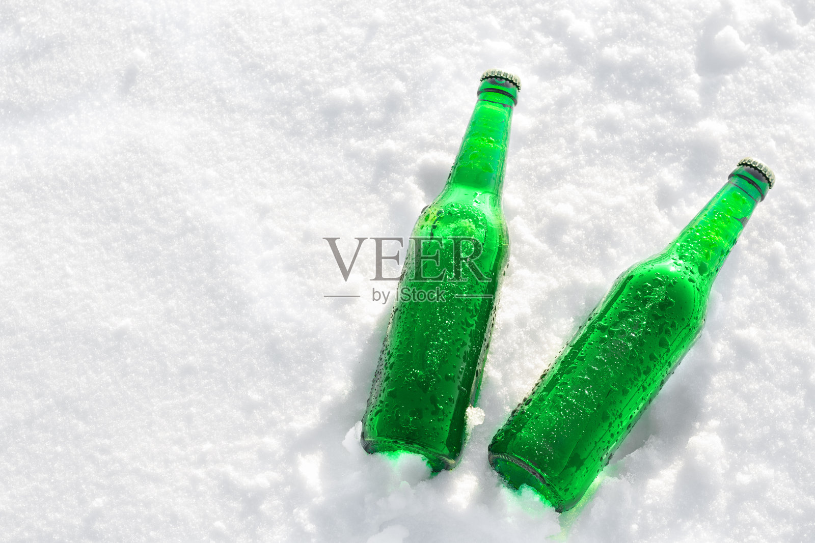 日落时分，雪地上放着两瓶冰镇啤酒照片摄影图片