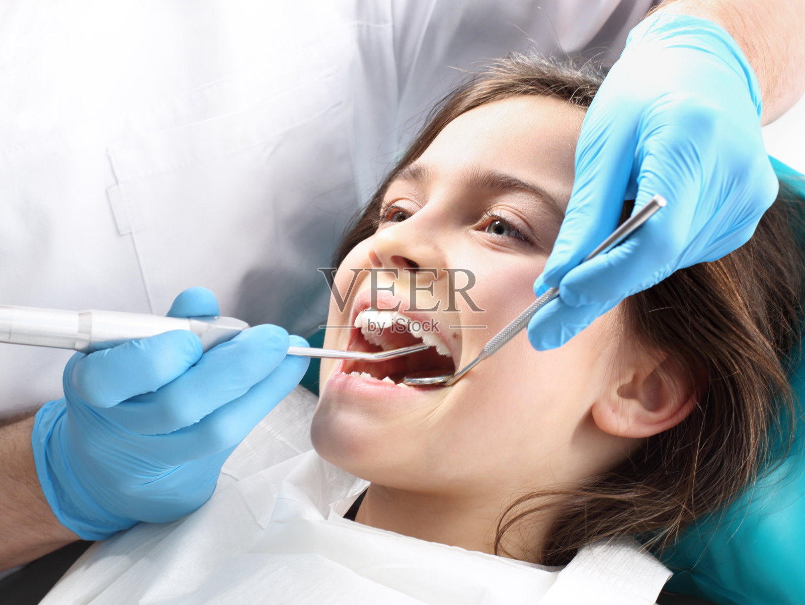 治疗牙齿时，牙科医生清理脱落的牙齿照片摄影图片