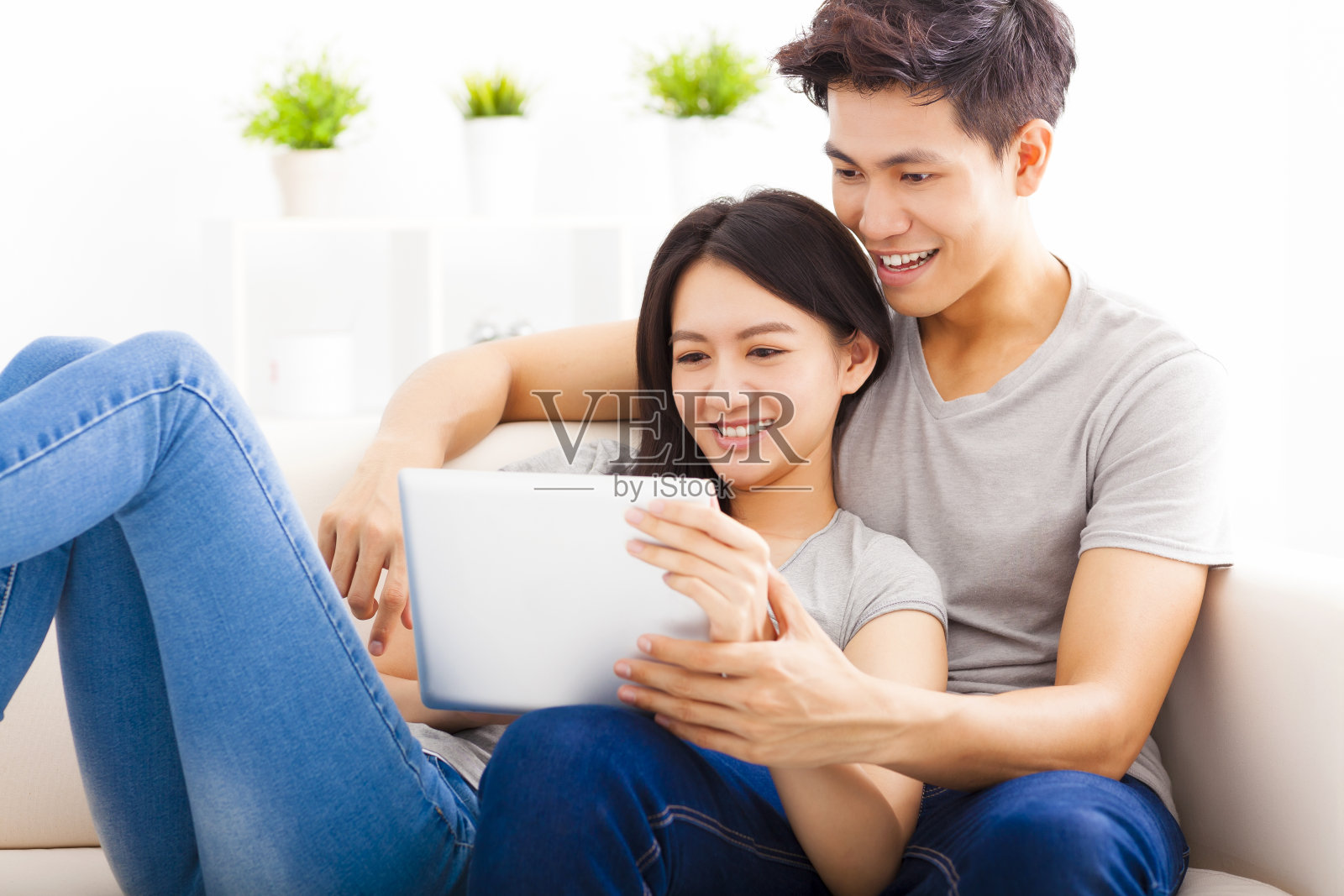 一对年轻夫妇在沙发上玩平板电脑照片摄影图片