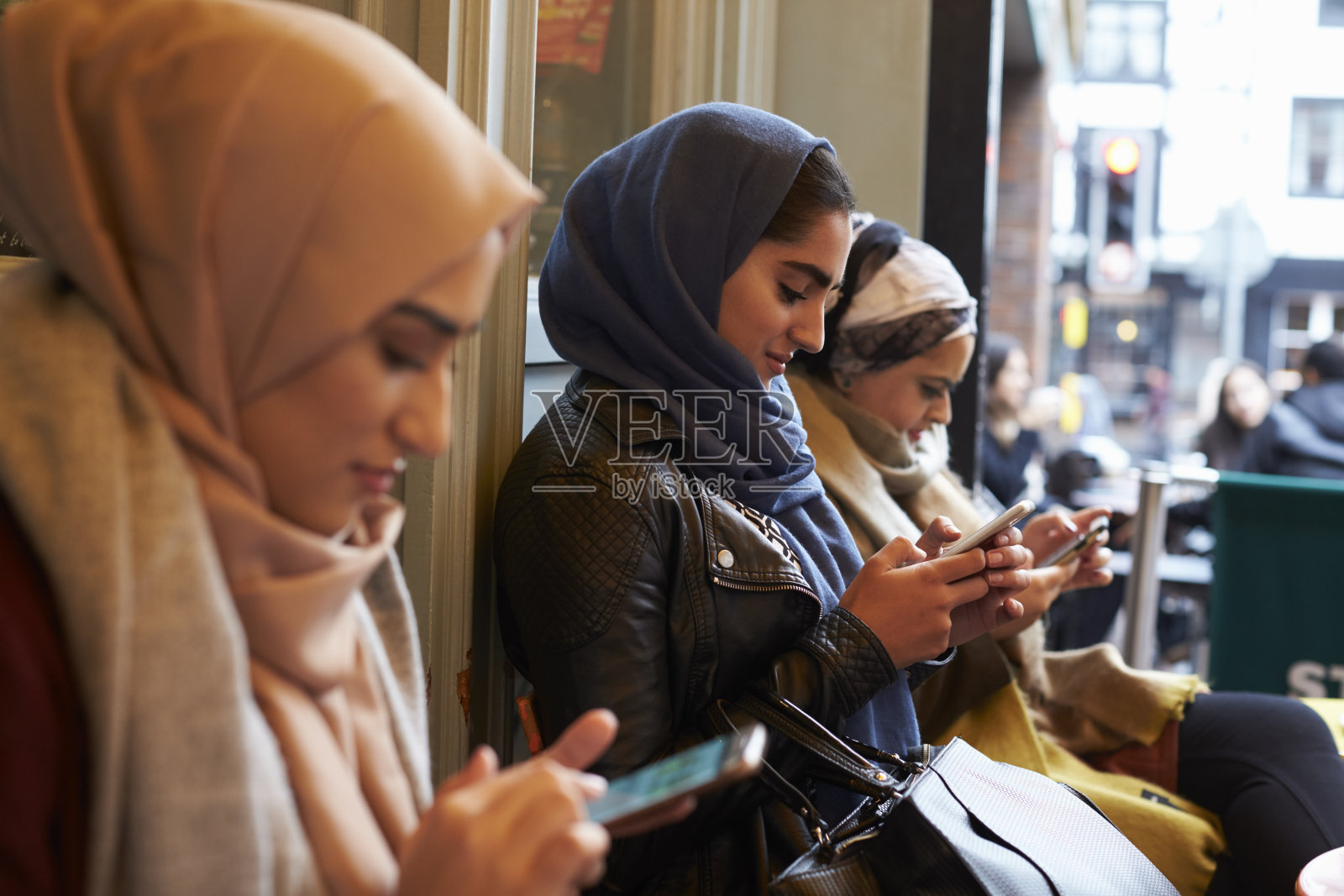 一群英国穆斯林妇女在咖啡店外发短信照片摄影图片