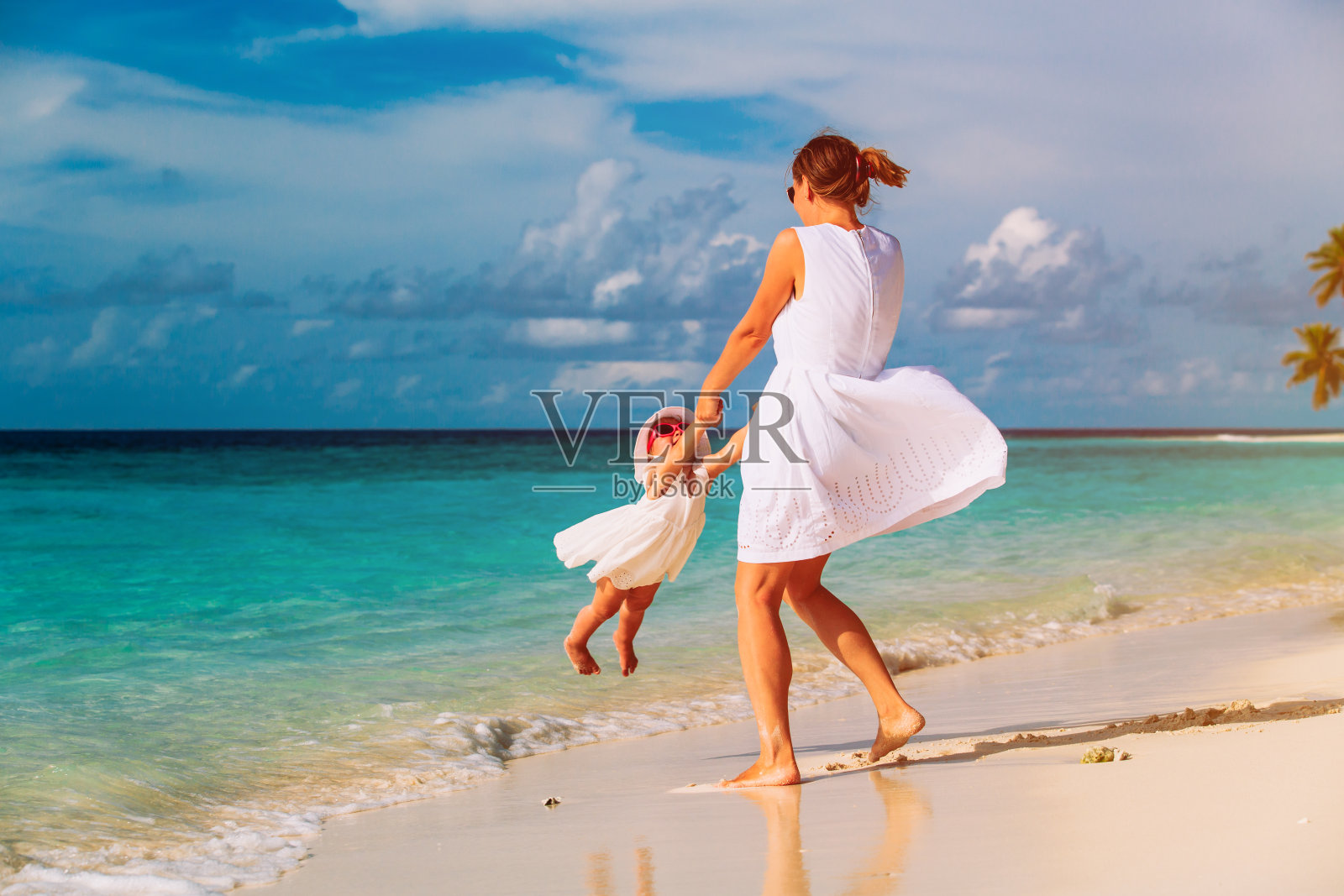 母亲和女儿在热带海滩上玩耍照片摄影图片
