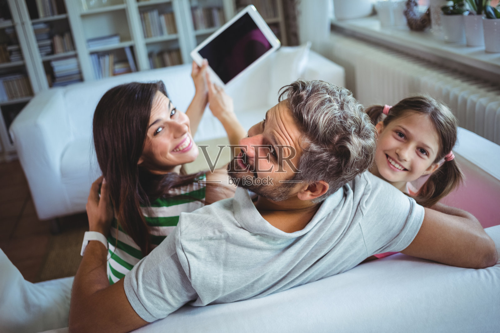 父母和女儿坐在沙发上，用平板电脑自拍照片摄影图片