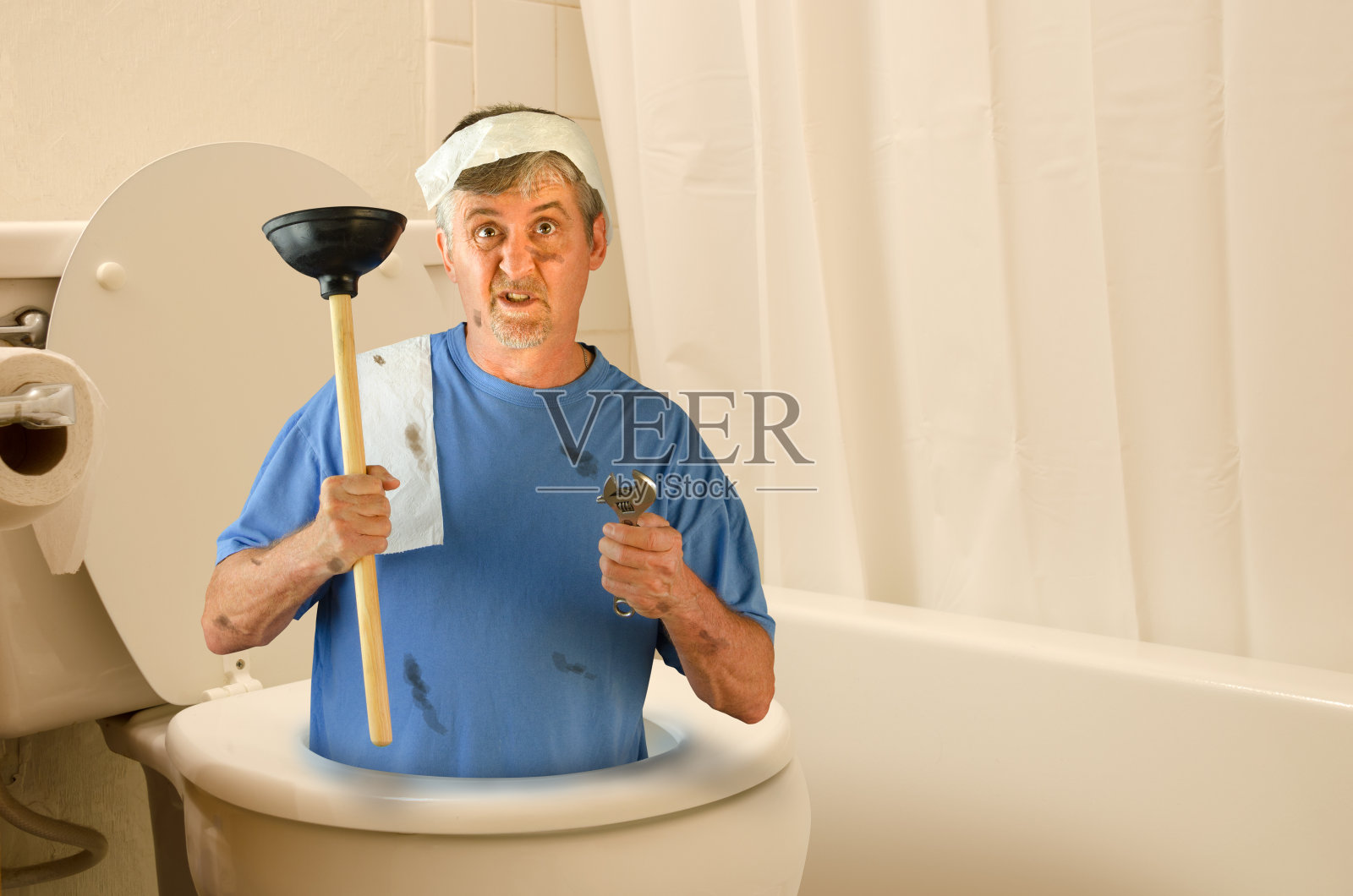 幽默的水管工在厕所内与工具和卫生纸照片摄影图片