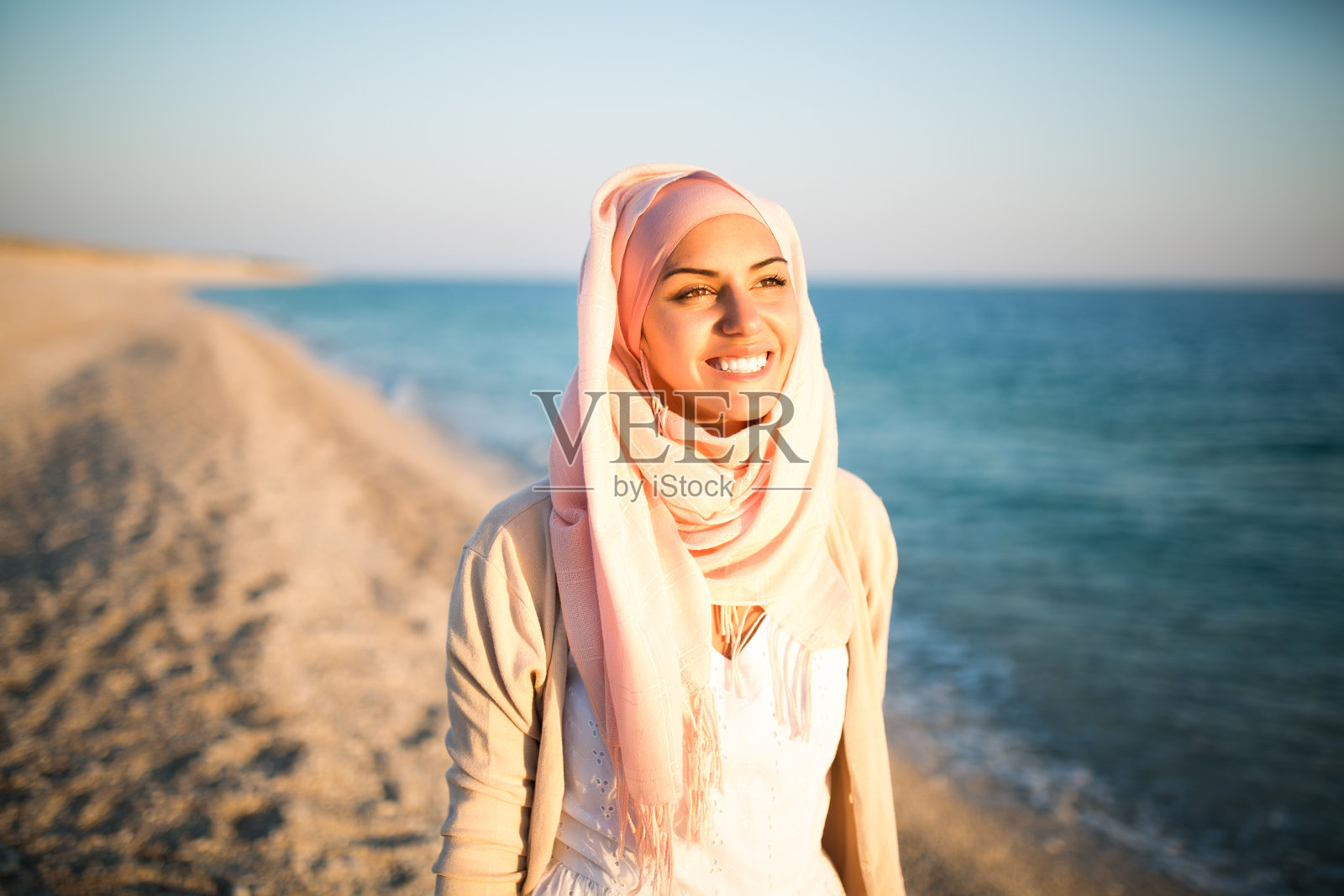 海滩上年轻美丽快乐的穆斯林女人照片摄影图片