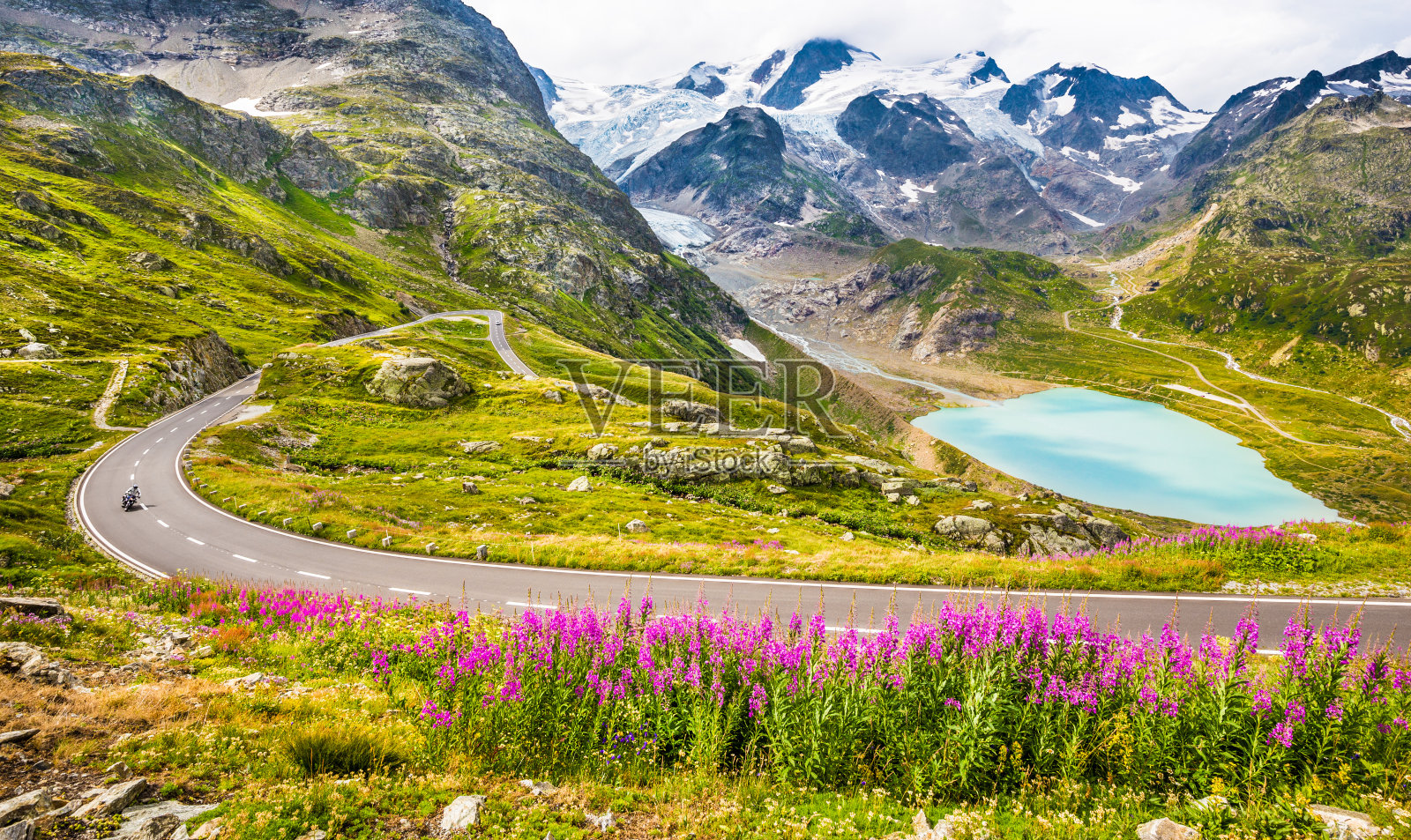 在阿尔卑斯山的山口公路上骑摩托车的人照片摄影图片