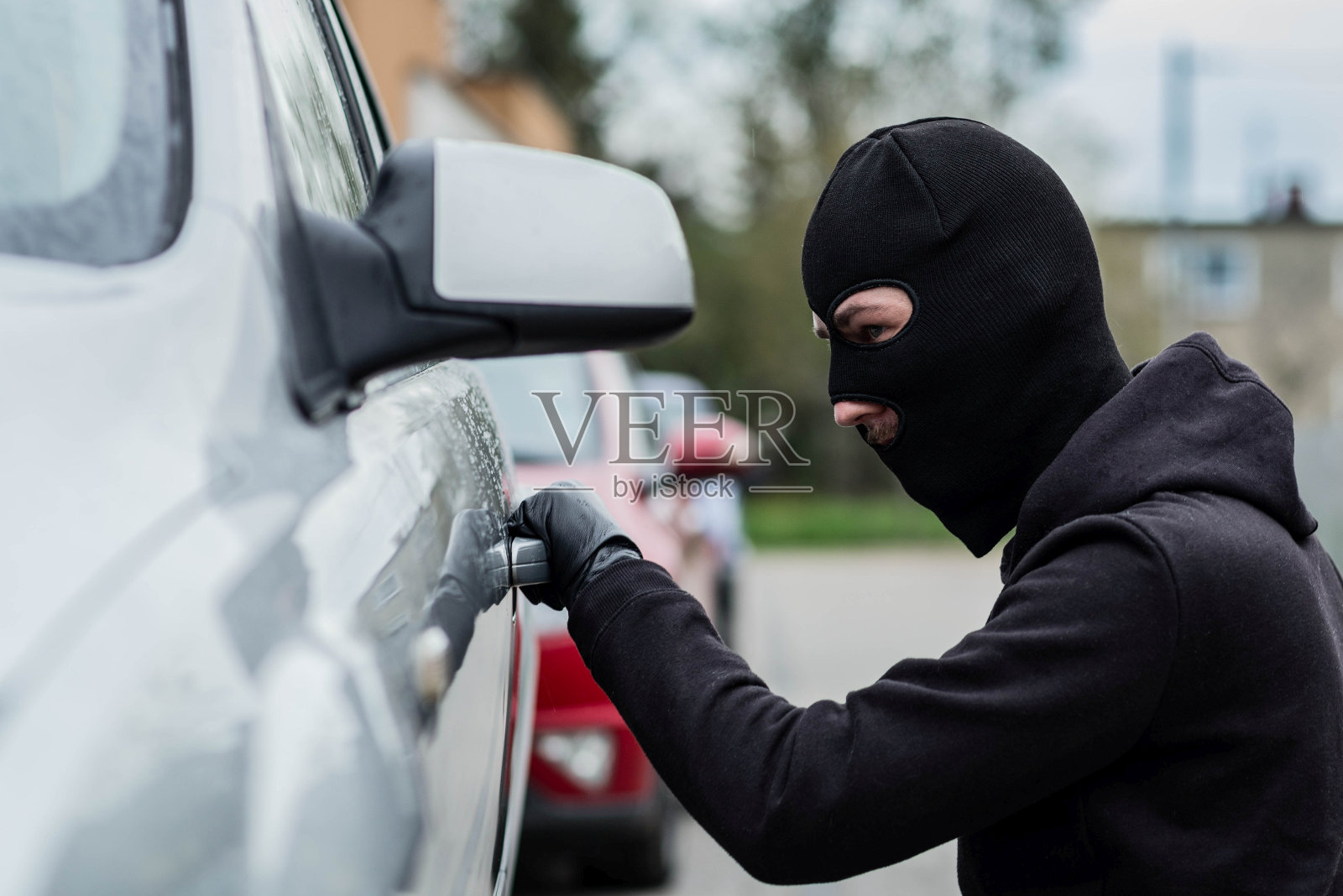 偷车贼拉一辆车的把手。照片摄影图片