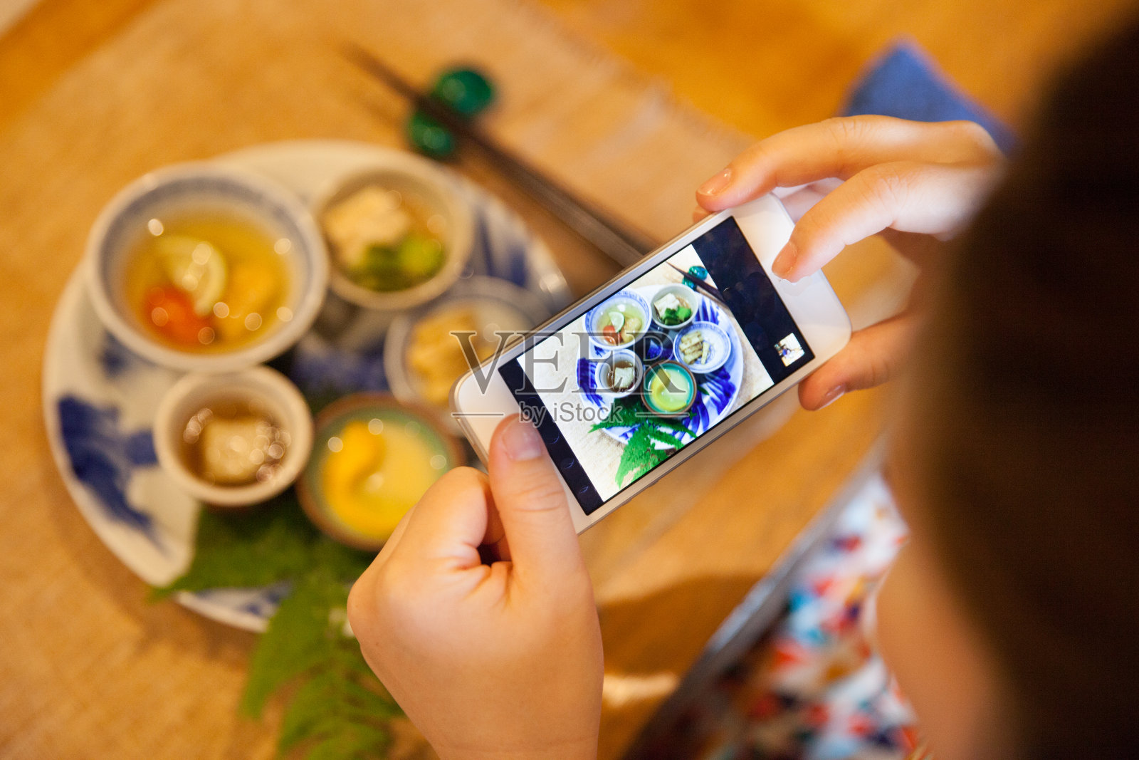 一名日本妇女在一家餐馆拍摄食物照片摄影图片