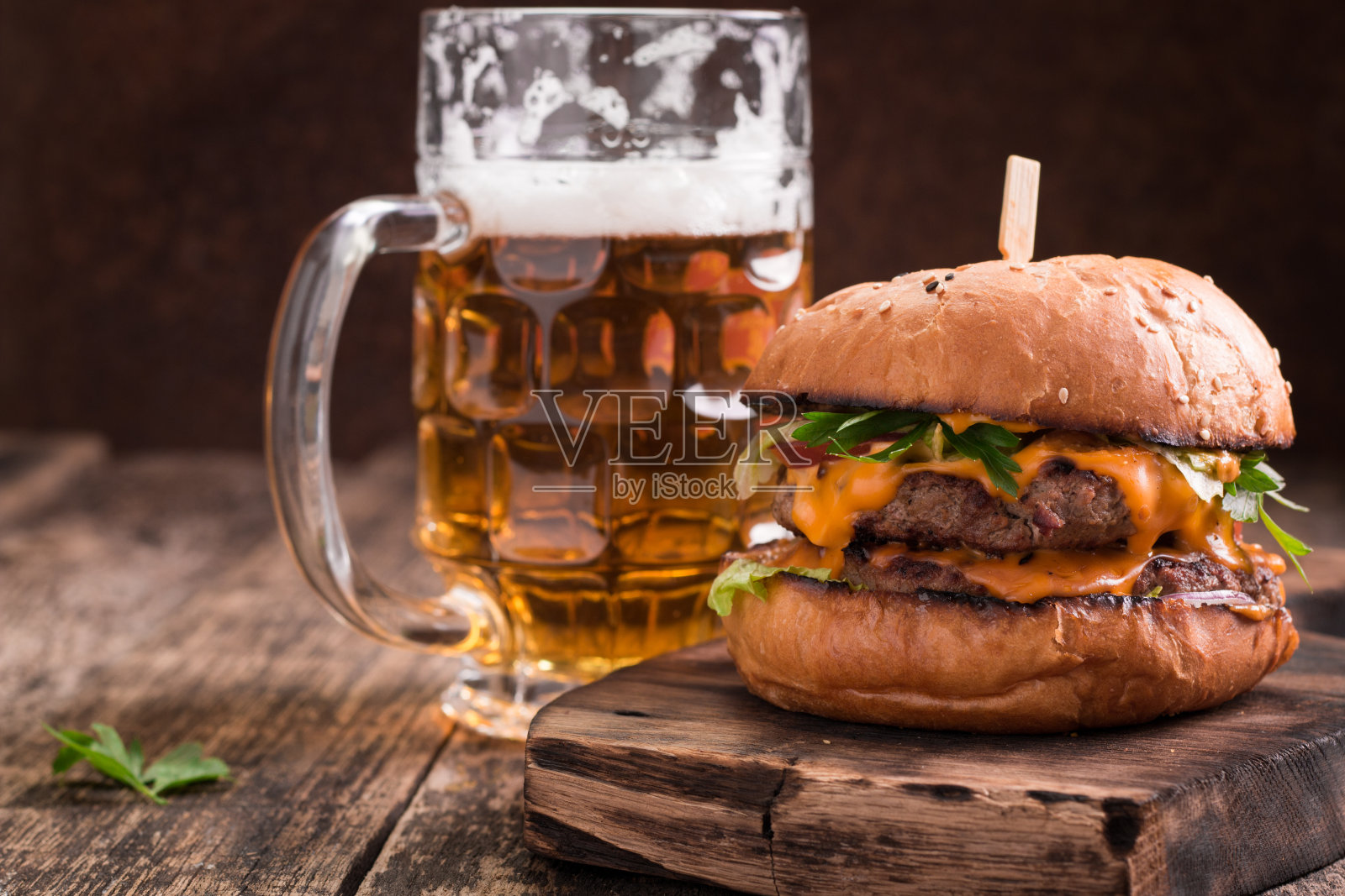 木桌上放着新鲜的汉堡和啤酒。照片摄影图片