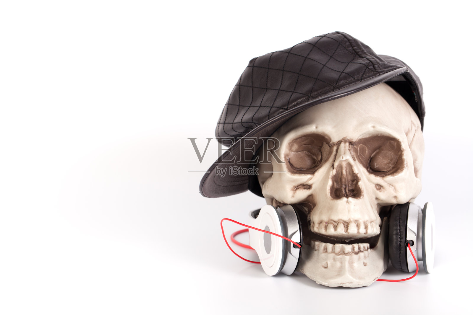 骷髅头戴黑帽子，用耳机听音乐照片摄影图片
