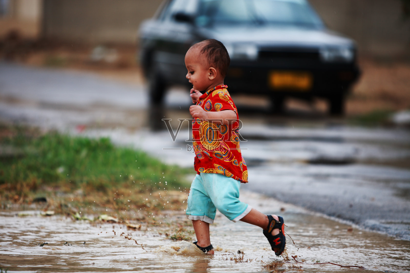 小男孩玩自由奔跑雨水水坑溅水照片摄影图片