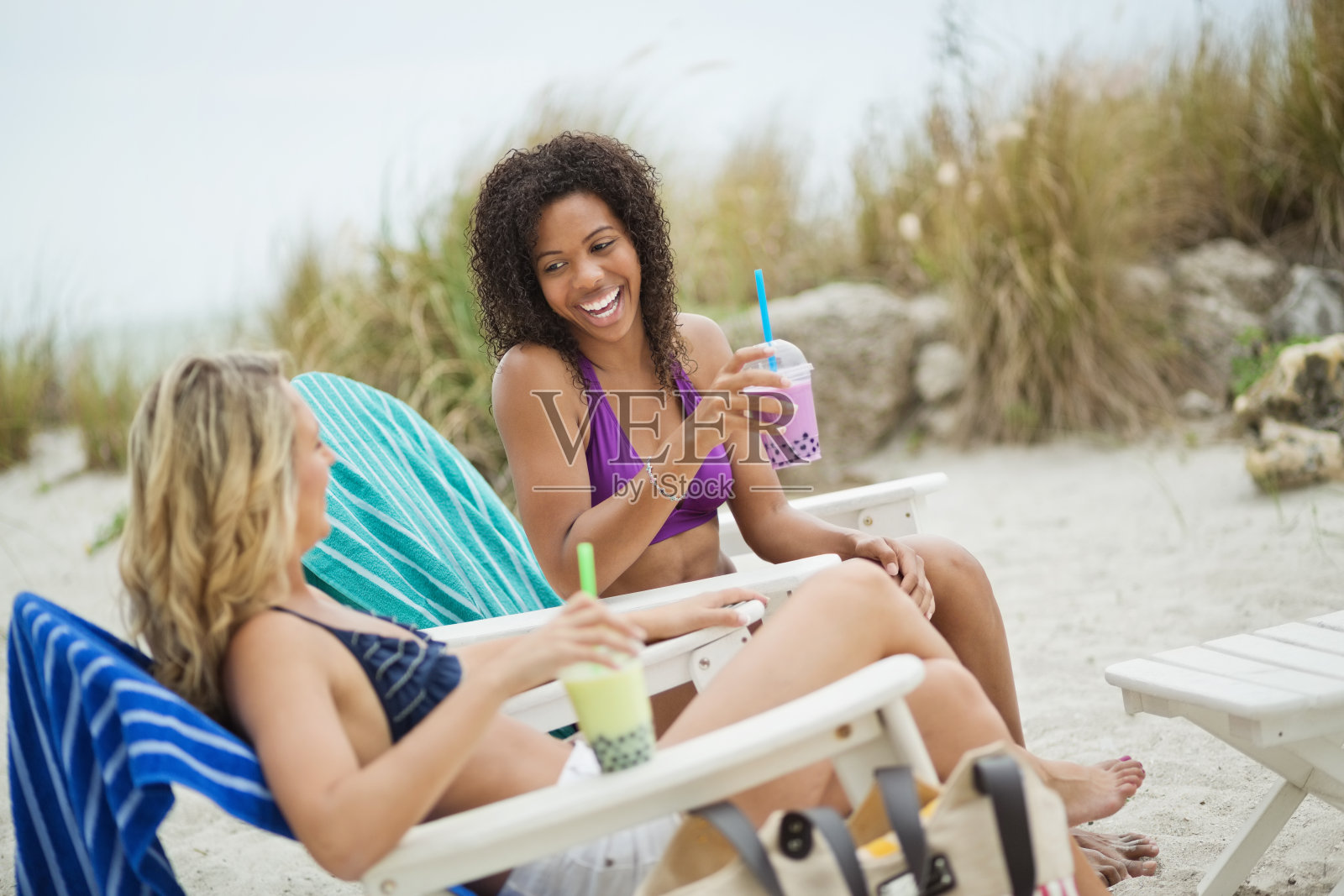 坐在沙滩椅上喝波巴牛奶的朋友照片摄影图片