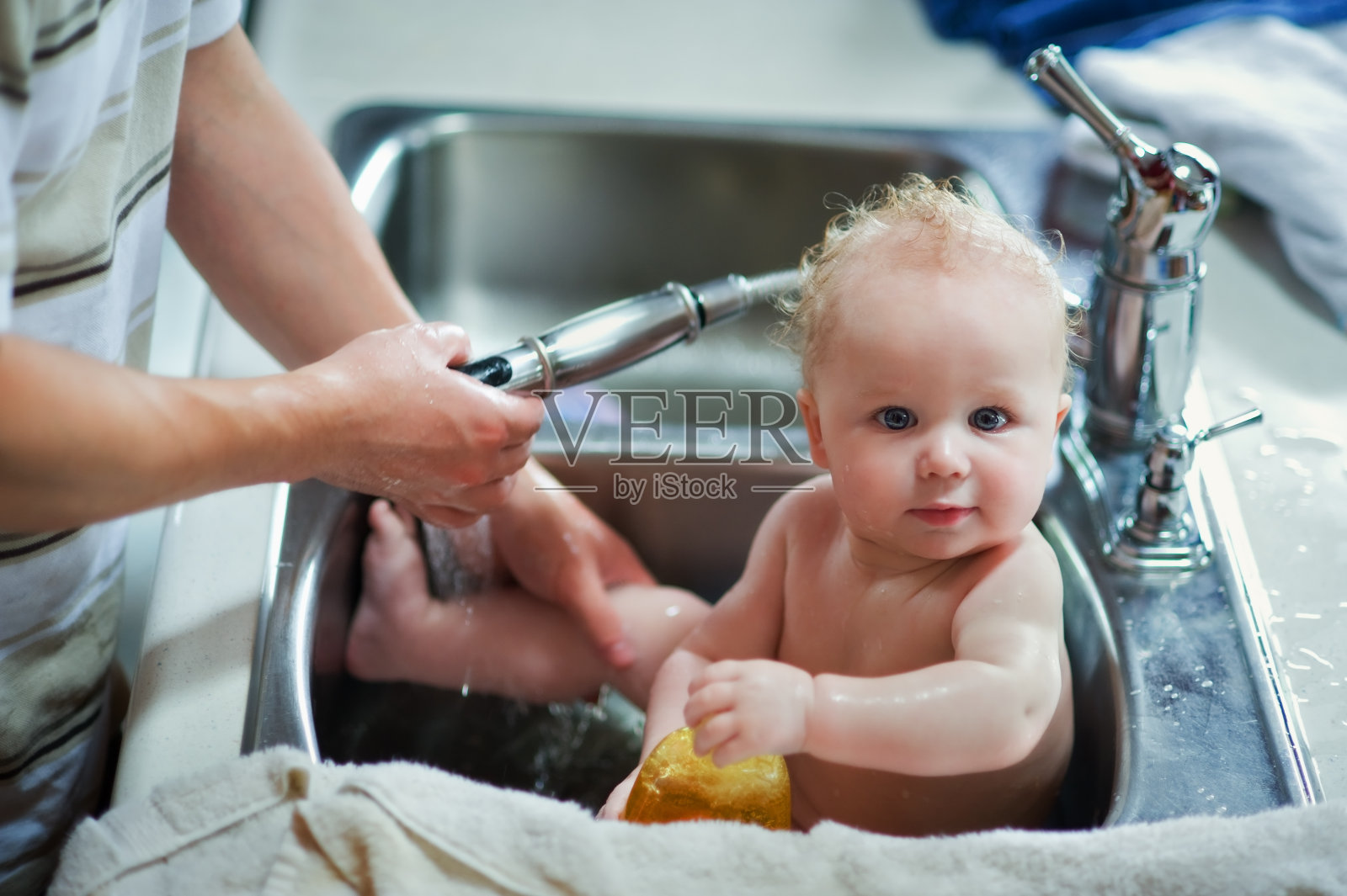 可爱的婴儿在厨房水槽里洗澡照片摄影图片