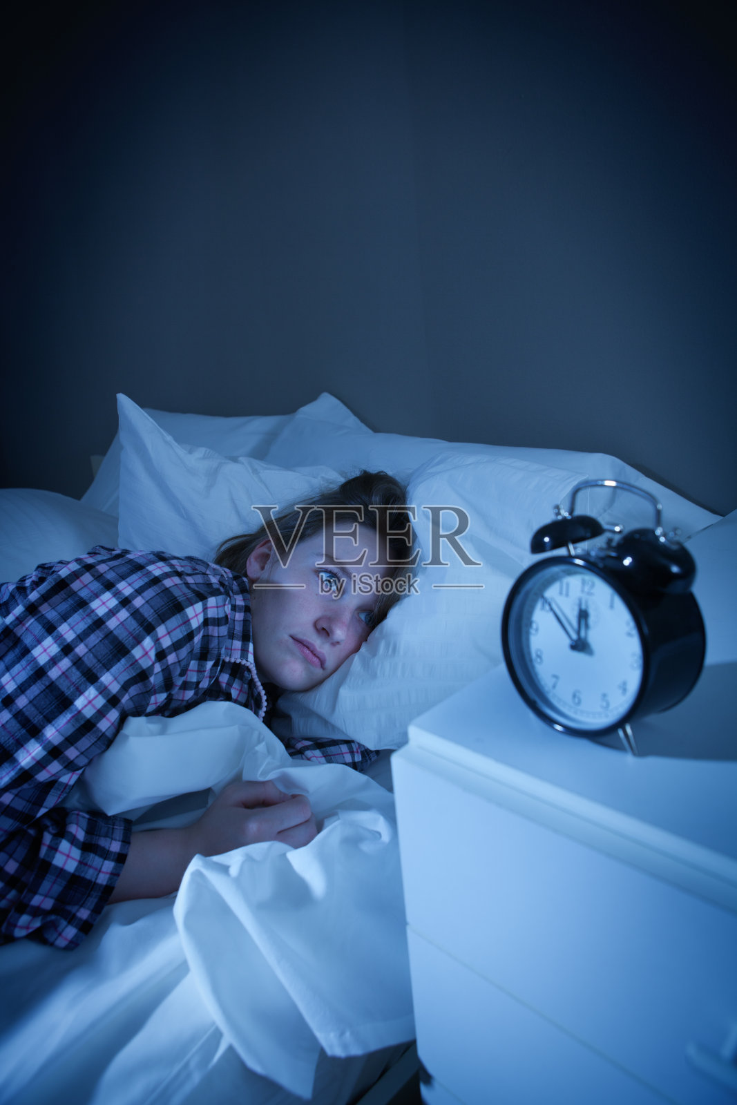 失眠的女人睡不着和闹钟照片摄影图片