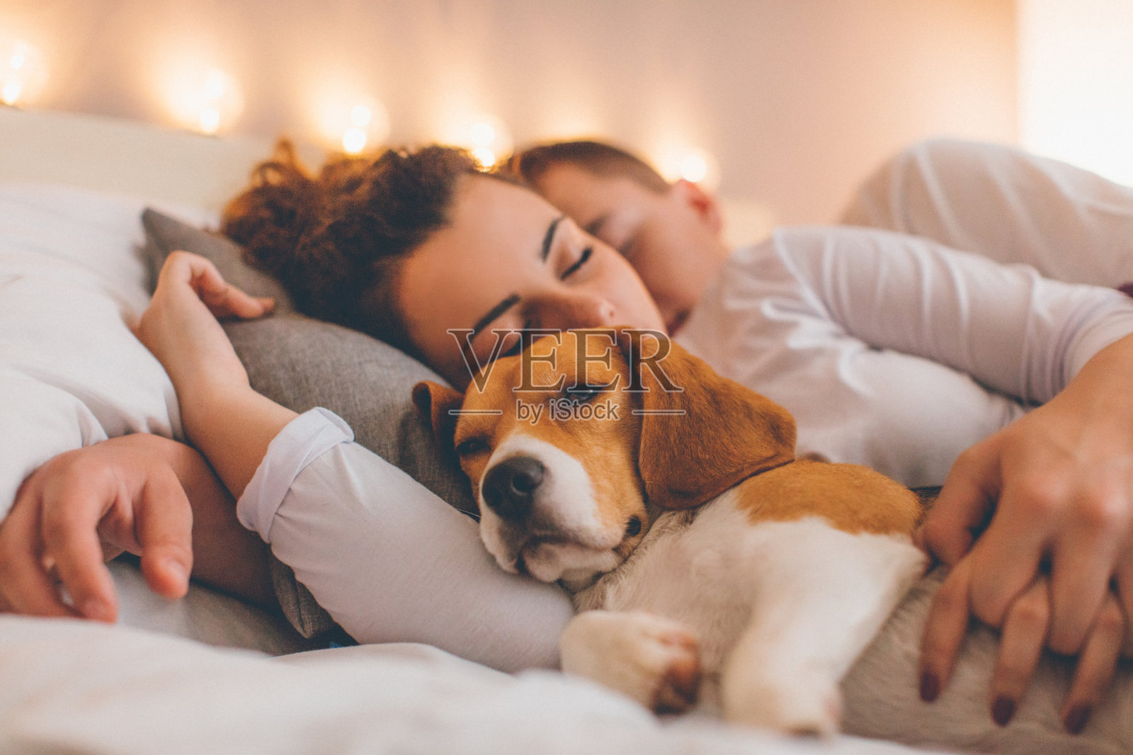一对年轻夫妇和她的宠物狗在床上休息照片摄影图片