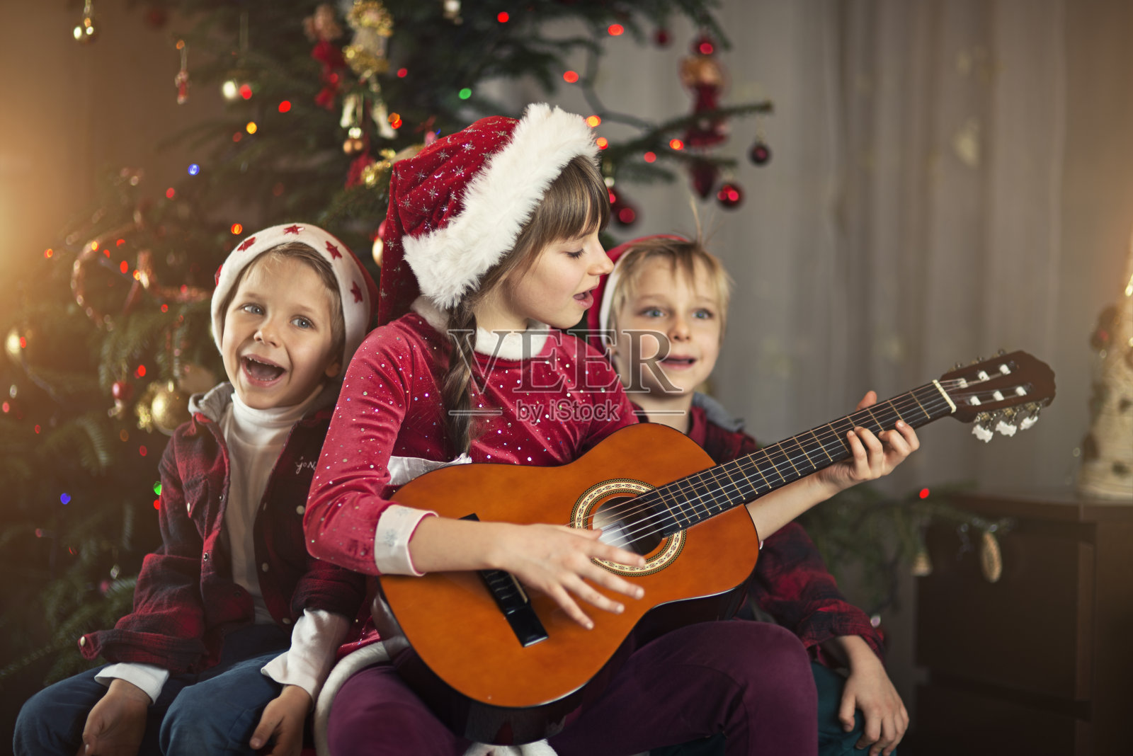 快乐的孩子们在圣诞帽拆圣诞礼物照片摄影图片_ID:351774277-Veer图库
