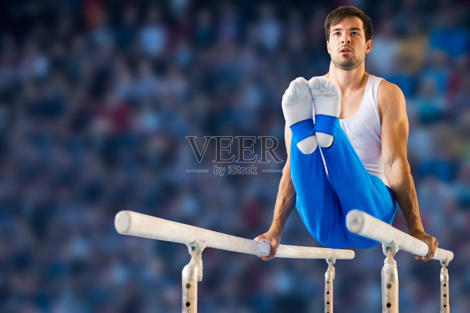 男子体操运动员在双杠上表演常规动作照片摄影图片