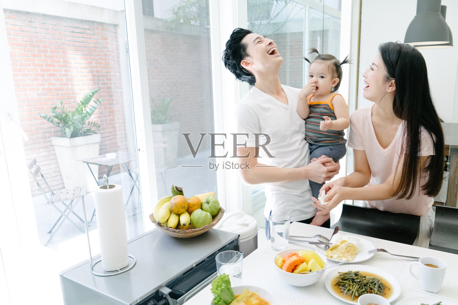年轻的一家人在厨房吃早餐照片摄影图片
