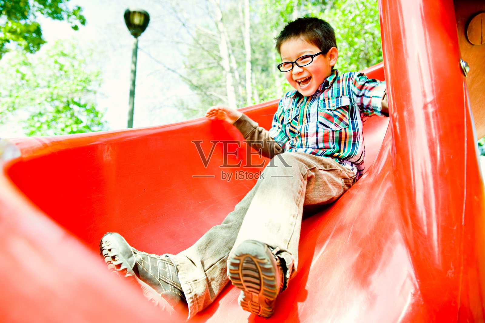 红色滑梯上的快乐男孩照片摄影图片