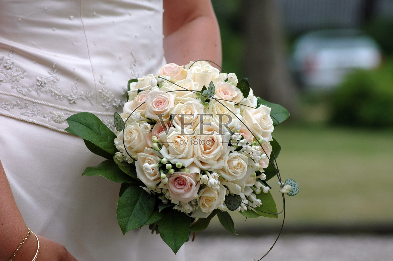 女子手持婚礼花束，旁边是白色婚纱照片摄影图片