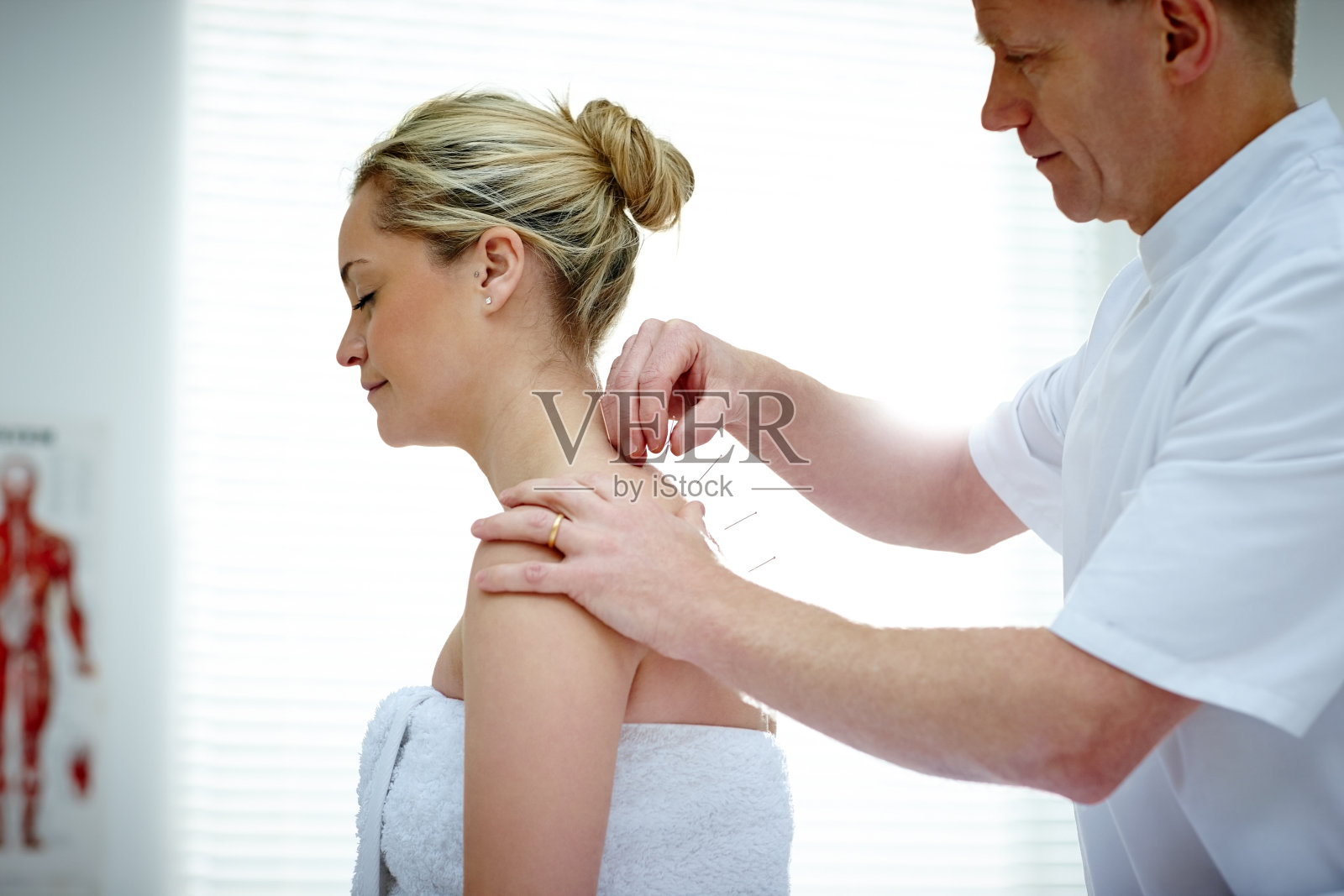 理疗师在一位女性病人的背部做针灸照片摄影图片