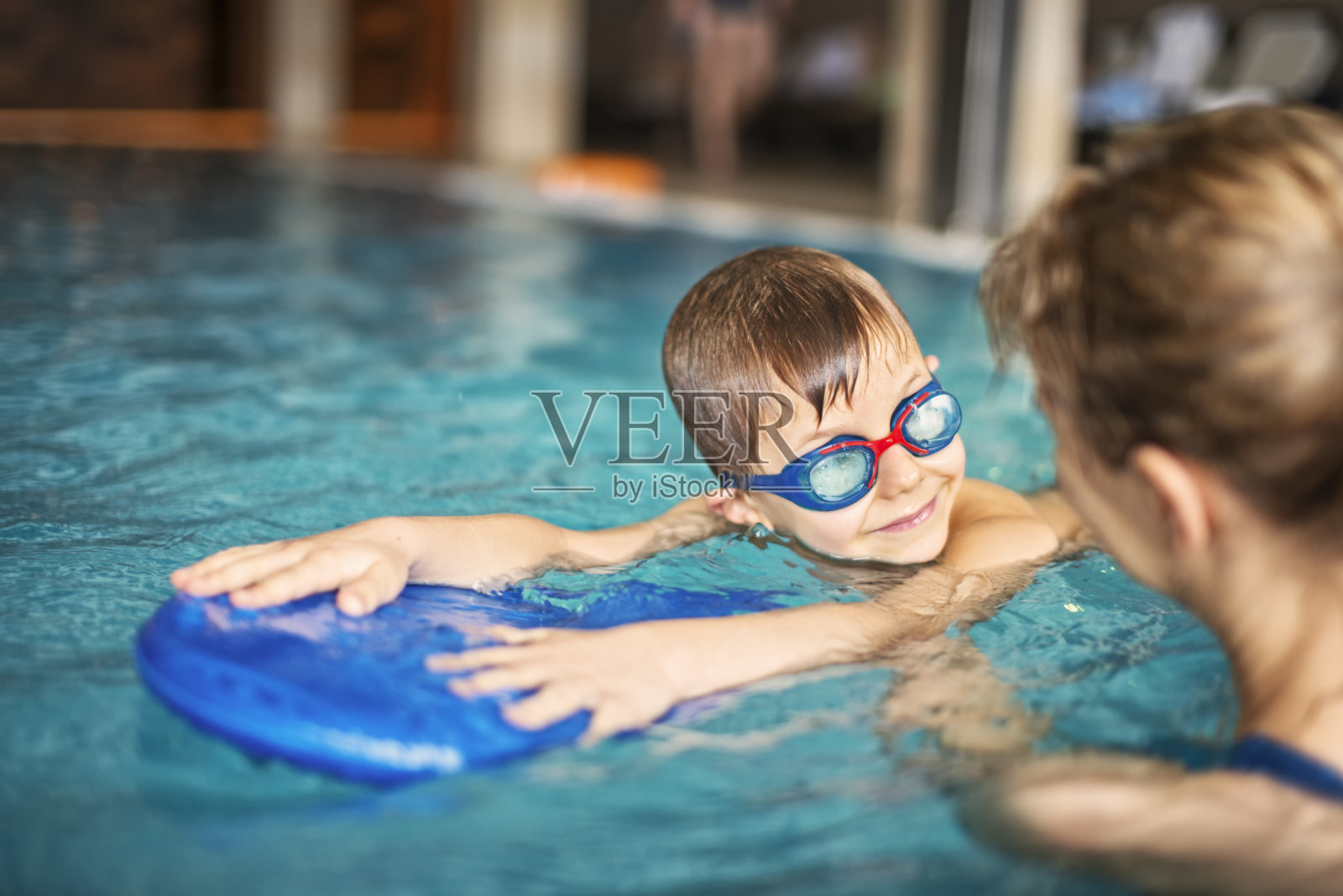小男孩在室内游泳池上游泳课照片摄影图片