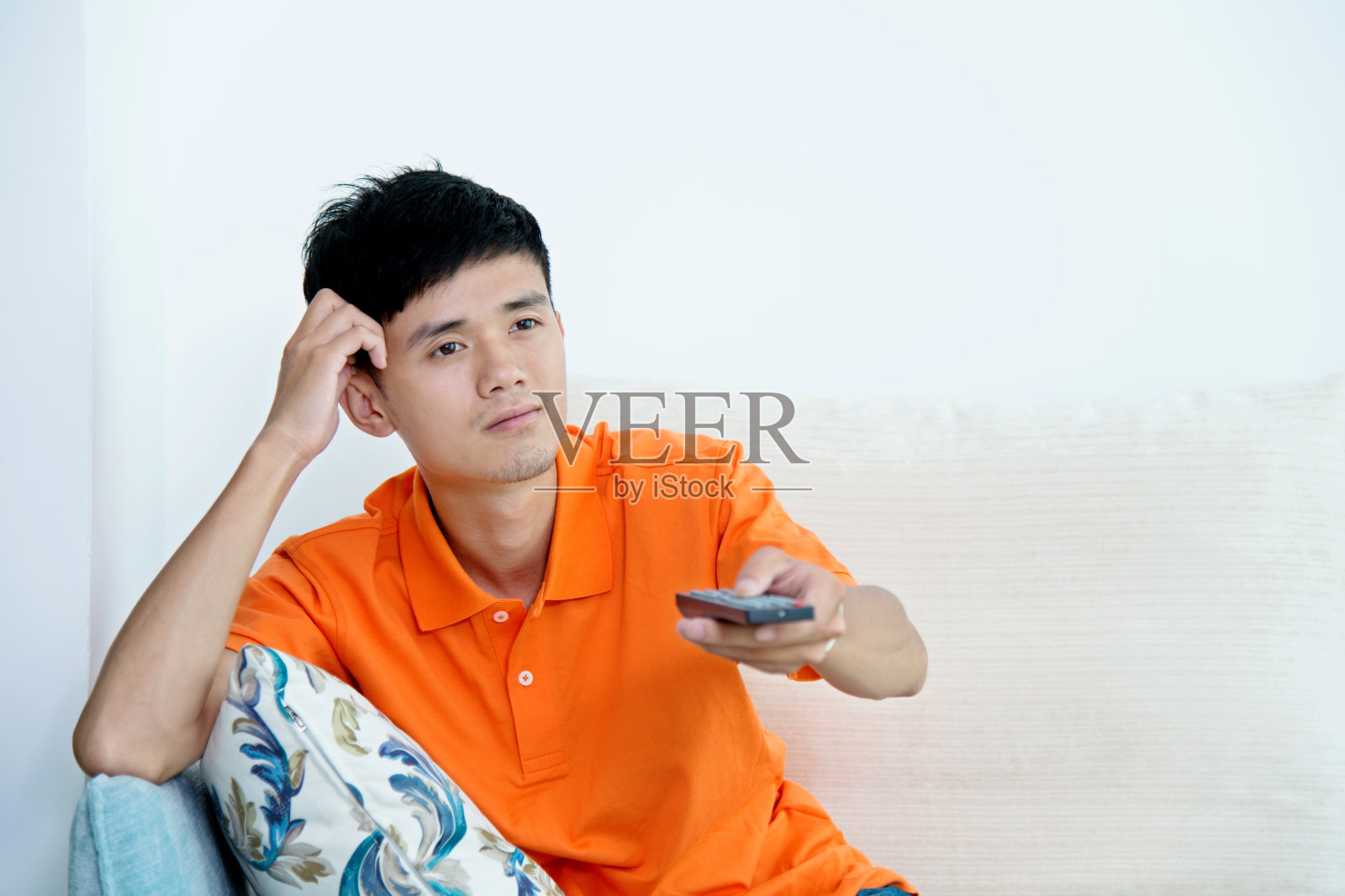 年轻的亚洲男人在沙发上看电视照片摄影图片