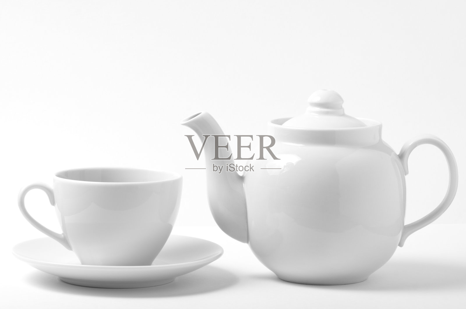 白色茶杯和茶托旁边的白色茶壶照片摄影图片