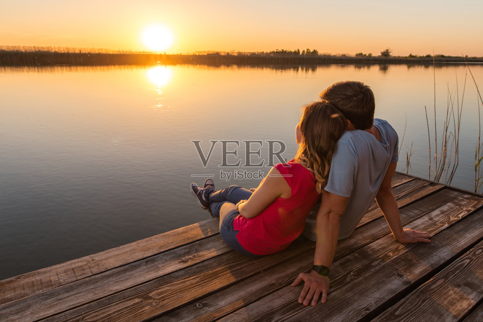 浪漫的情侣在湖边欣赏日落。照片摄影图片