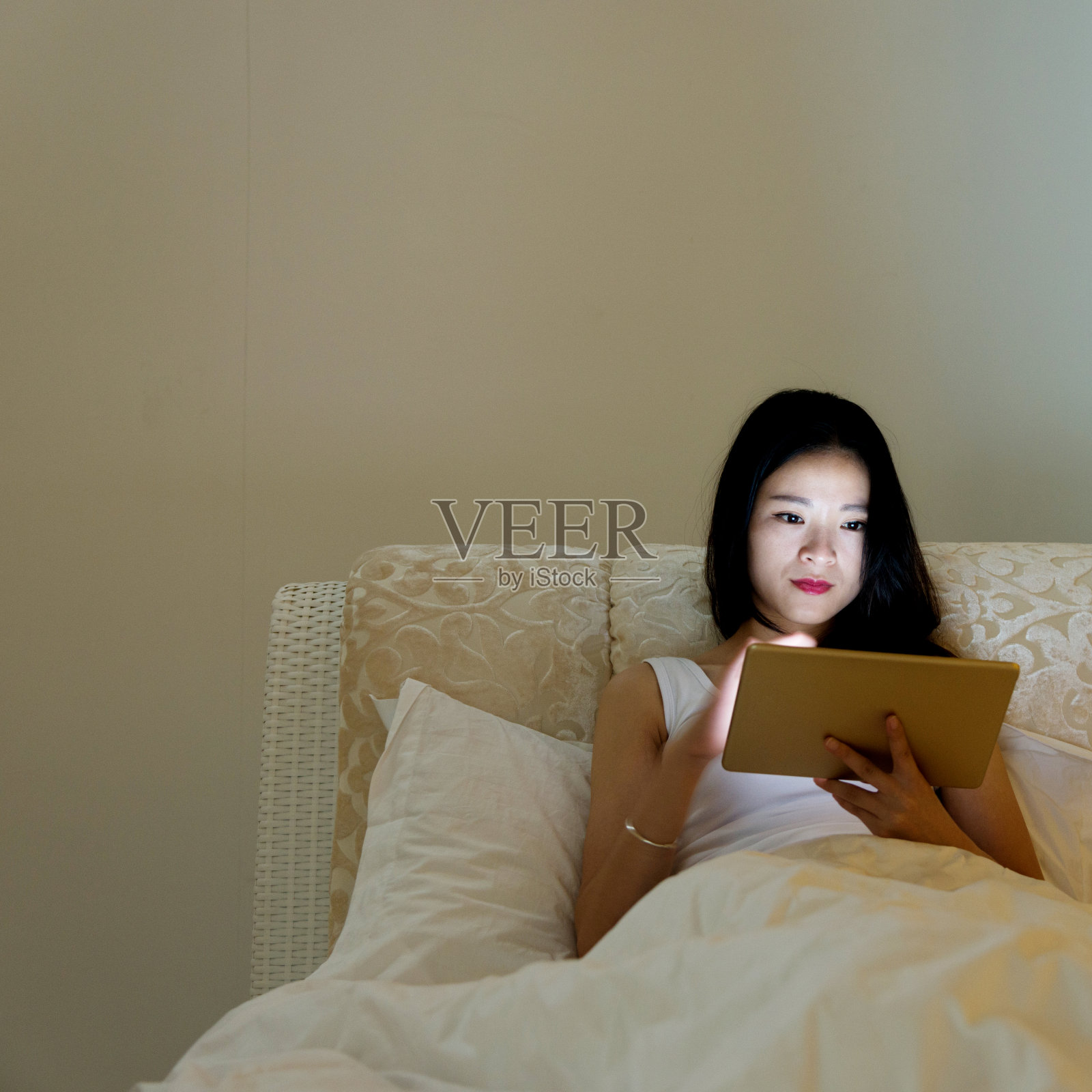 晚上在床上用平板电脑的女人照片摄影图片