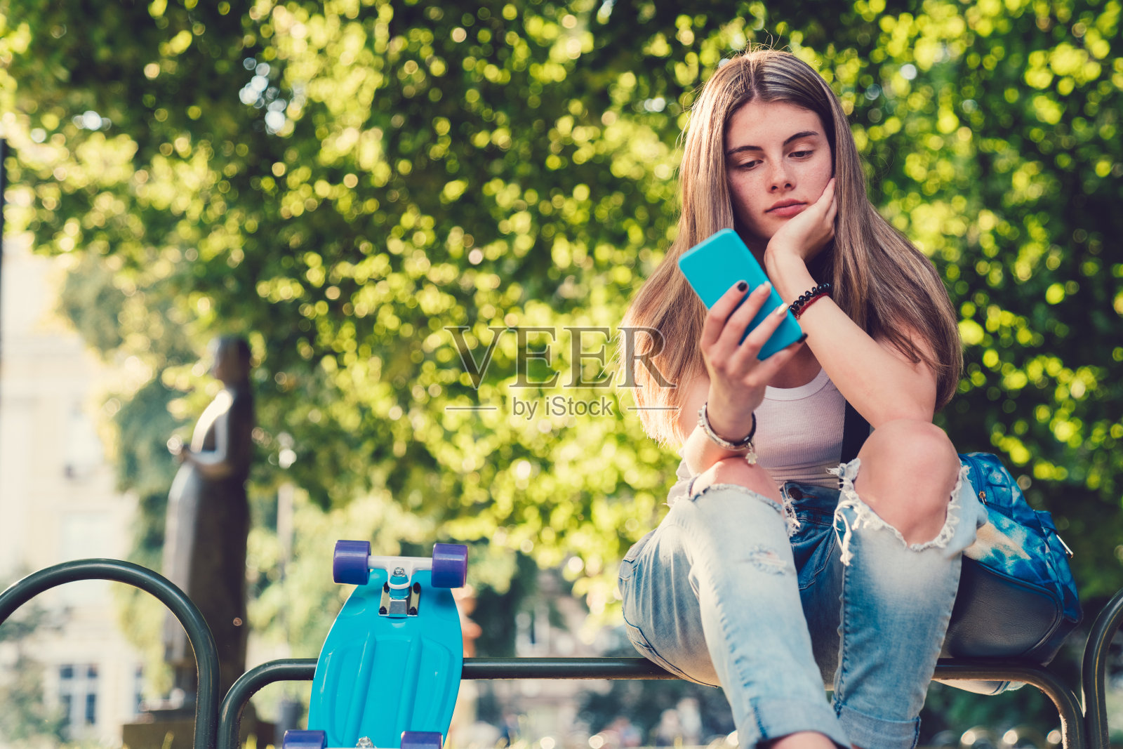 女孩用滑板在城市公园发短信照片摄影图片