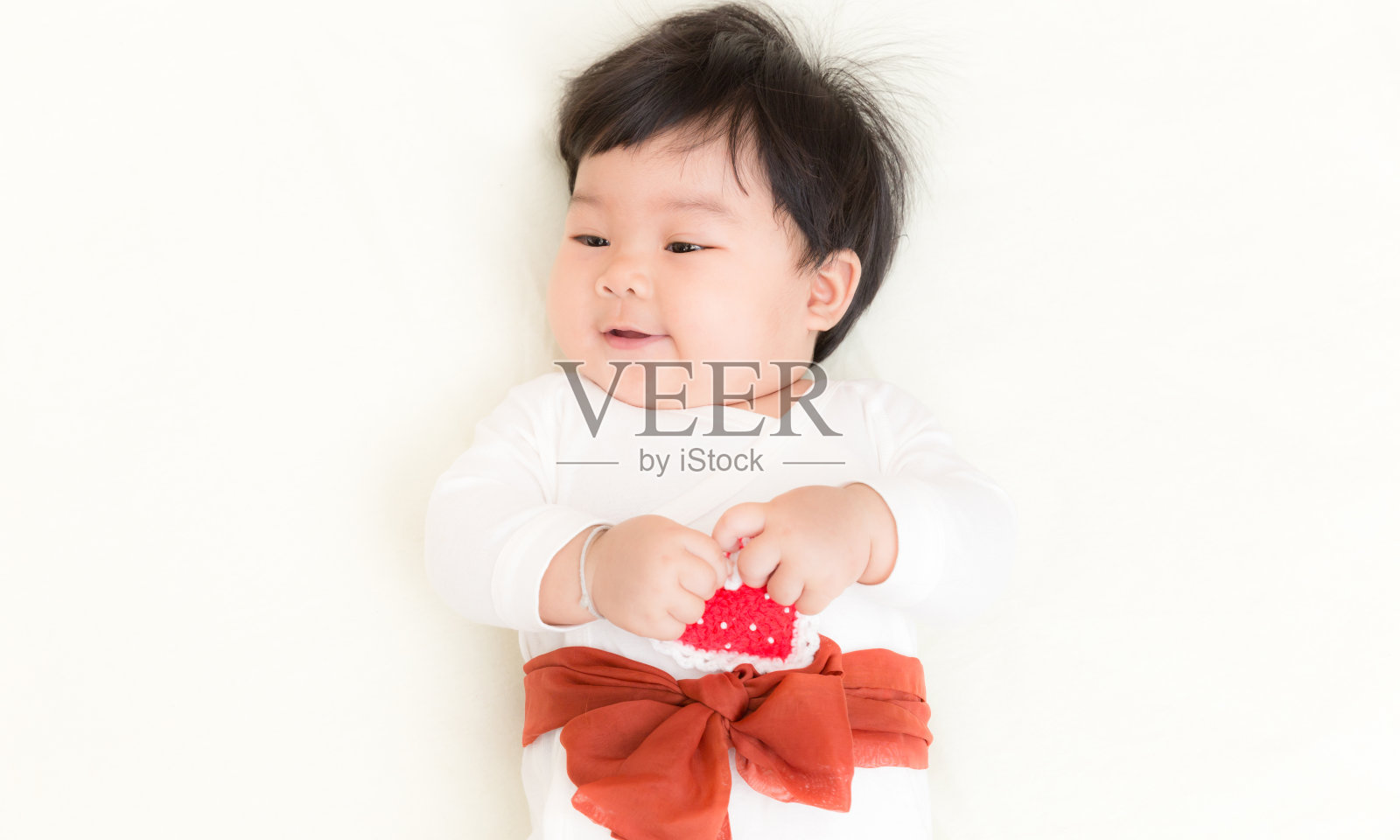 亚洲婴儿可爱的女孩在床上微笑为背景。照片摄影图片