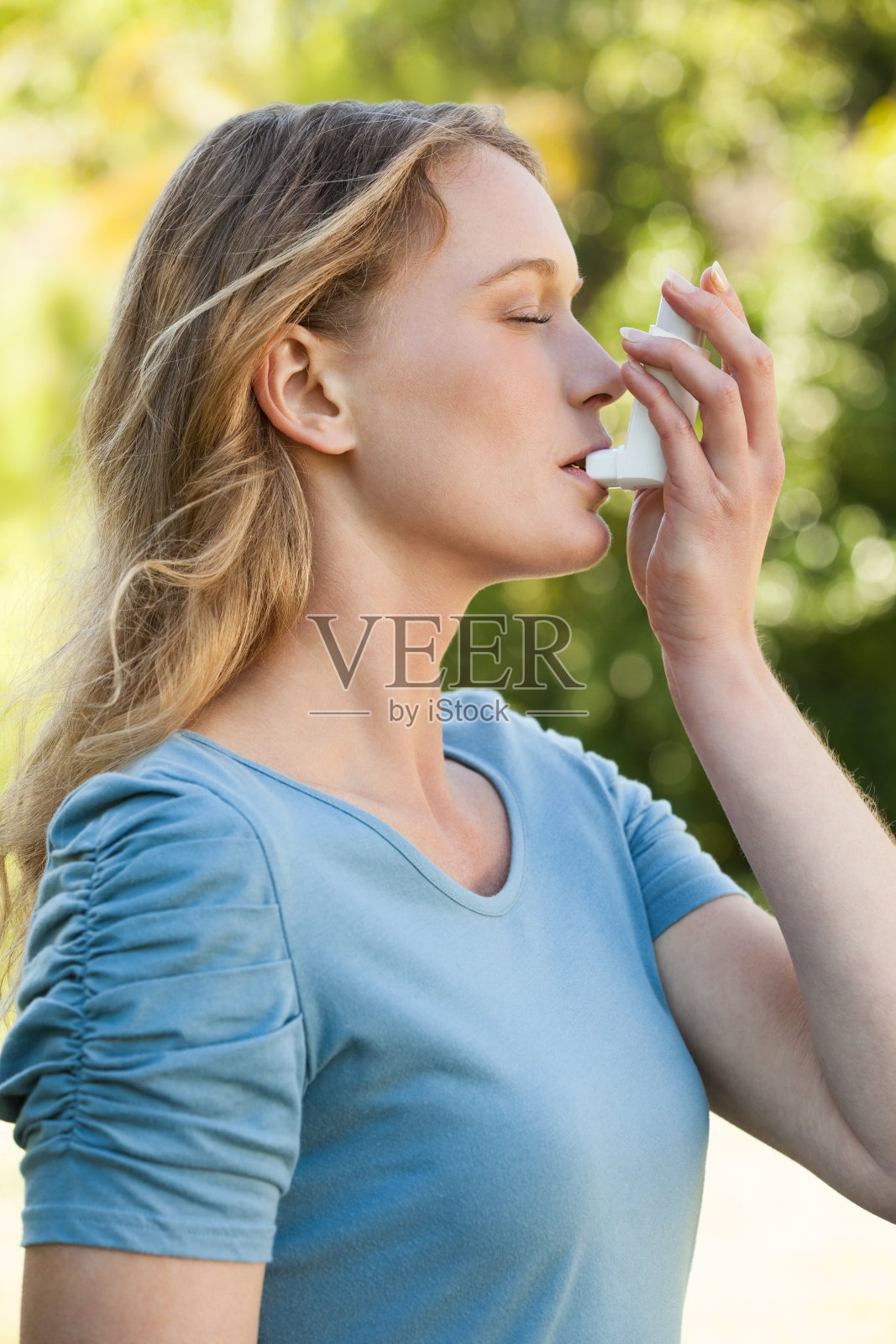 年轻女子在公园使用哮喘吸入器照片摄影图片
