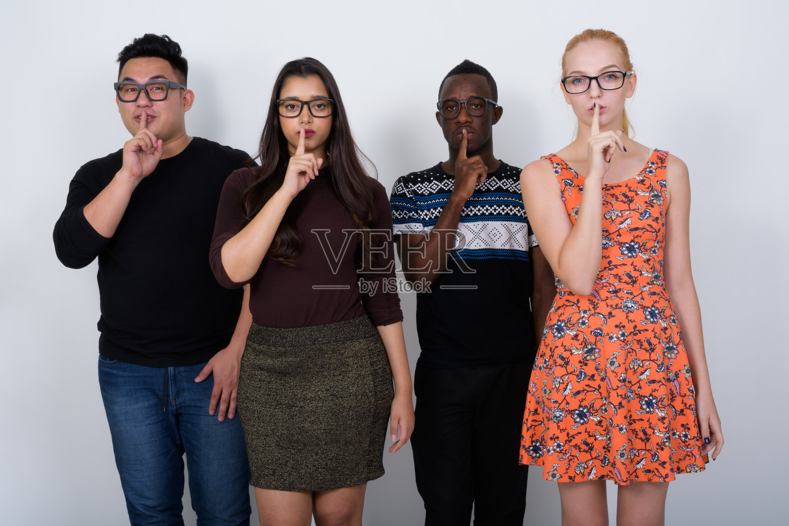 工作室拍摄了一组不同种族的朋友，他们戴着眼镜，手指放在嘴唇上照片摄影图片