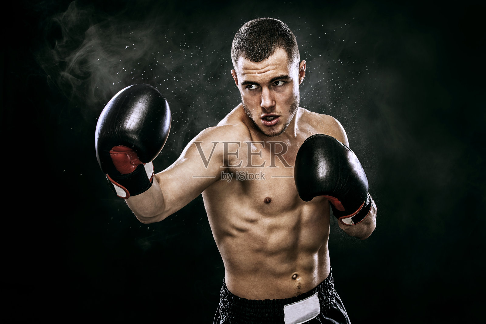 运动员泰拳拳击手在拳击笼子里戴着手套战斗。孤立在黑色背景与烟雾。副本的空间。照片摄影图片