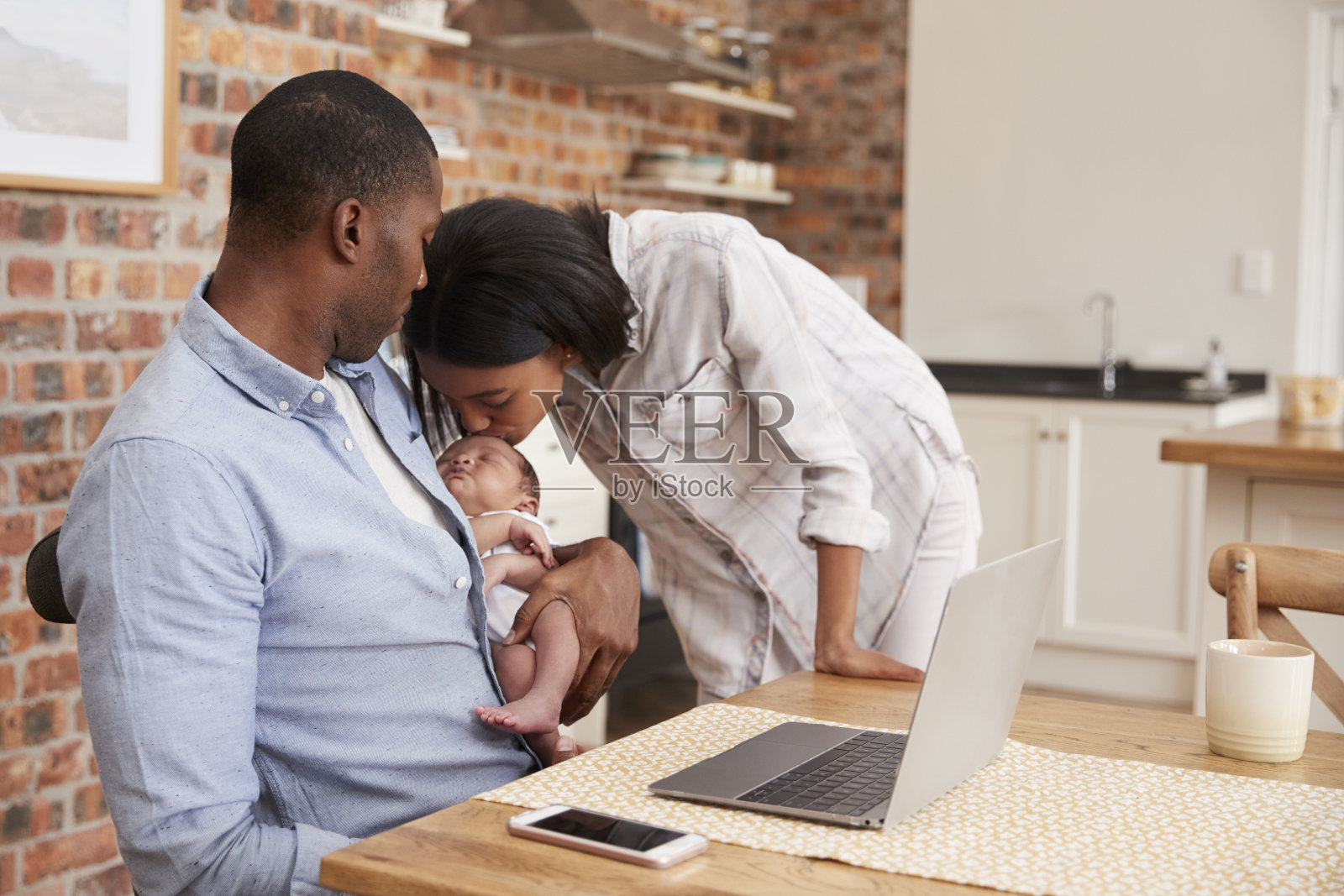 用笔记本电脑工作的父亲抱着刚出生的儿子和母亲照片摄影图片