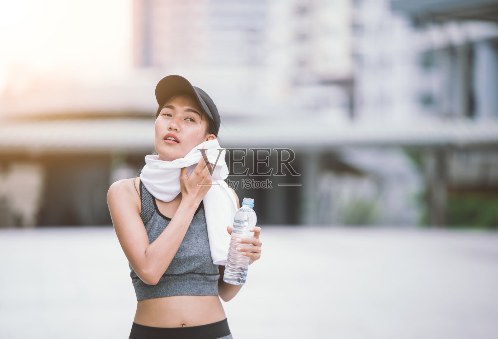 擦汗口渴的女性慢跑者在训练后饮用淡水。在城市公园户外运动的年轻女运动员。与复制空间照片摄影图片